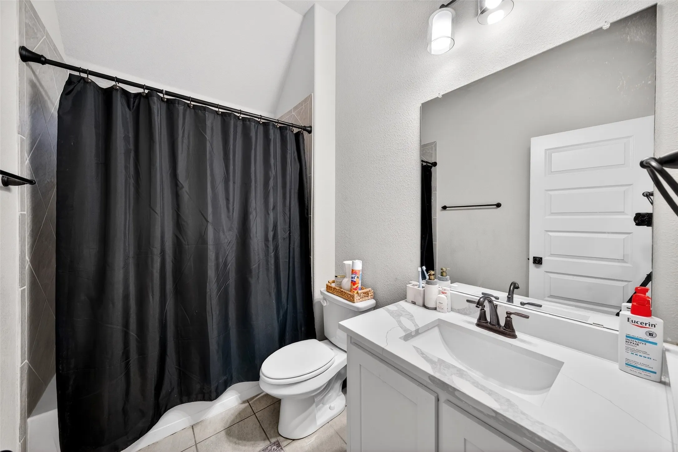 Bathroom featuring a white vanity with an integrated sink, bronze-finish faucet, and a large wall-mounted mirror