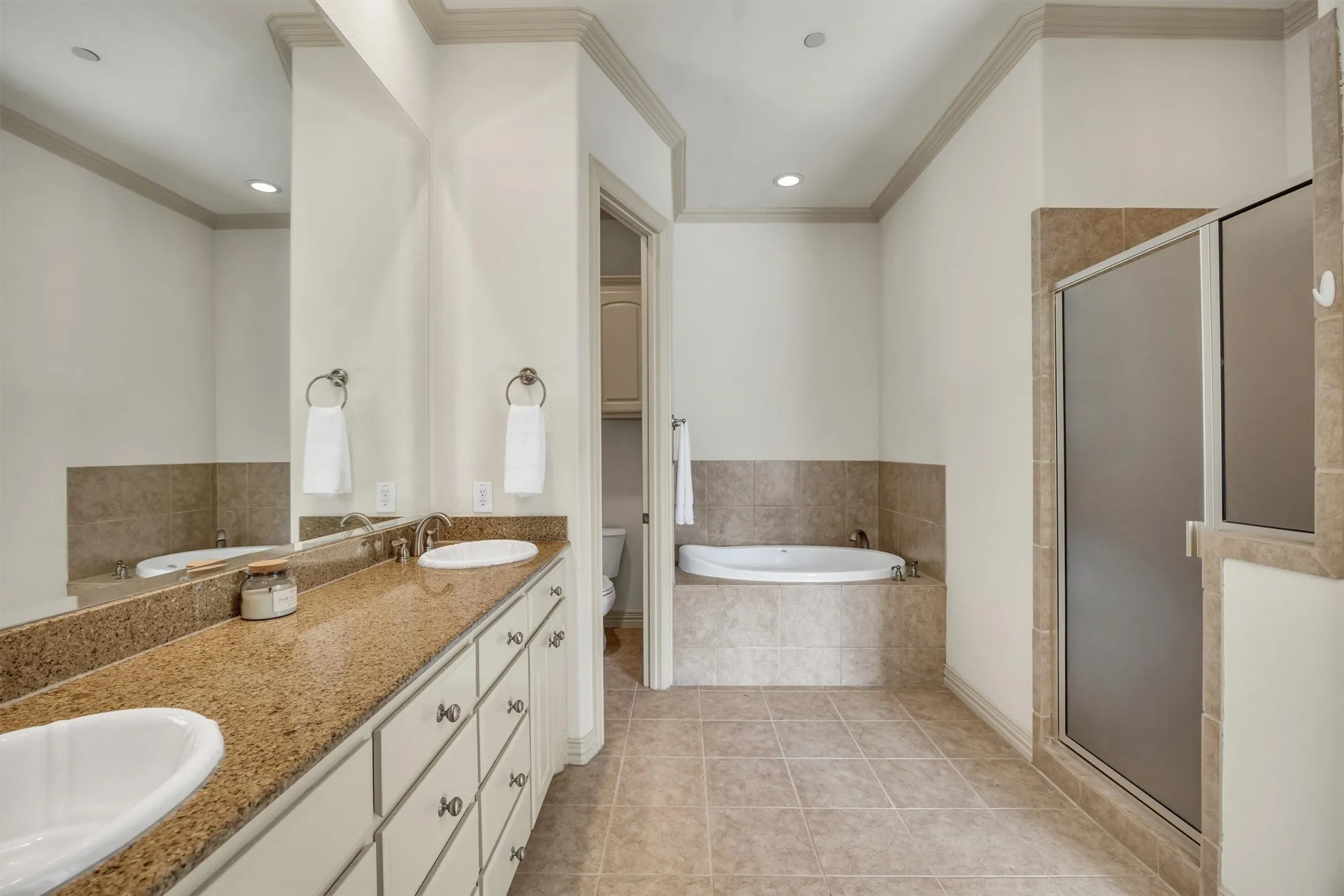 Dual vanity with light-toned countertop and undermount sinks, tiled flooring, recessed lighting, built-in bathtub, and a glass-enclosed shower