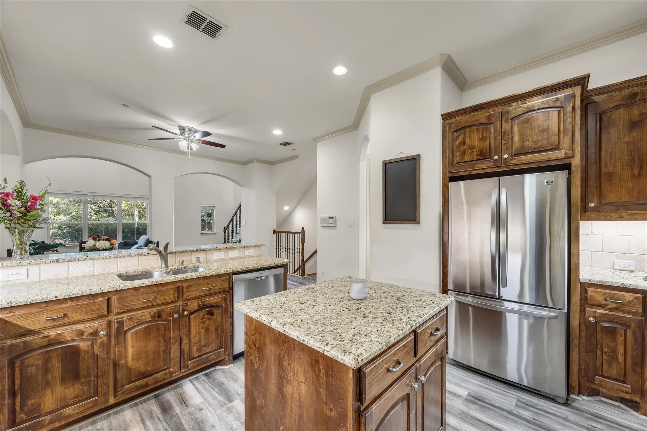 Kitchen featuring wood-finish flooring, wood cabinetry, granite countertops, and stainless steel appliances