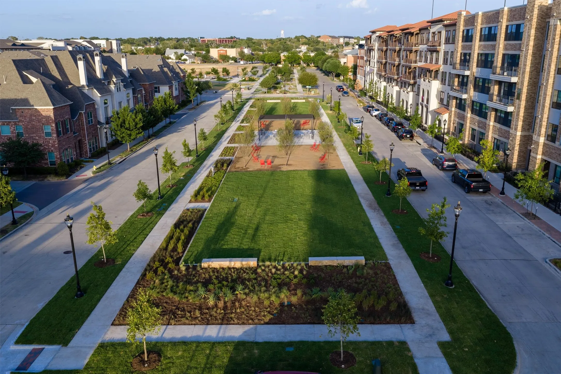 Central green space with manicured lawn, established plantings, and paved walkways