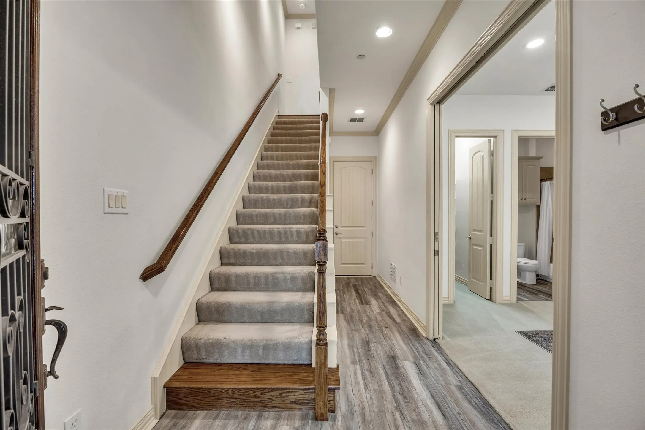 Carpeted staircase with wood handrail, recessed lighting, and wood-finish flooring