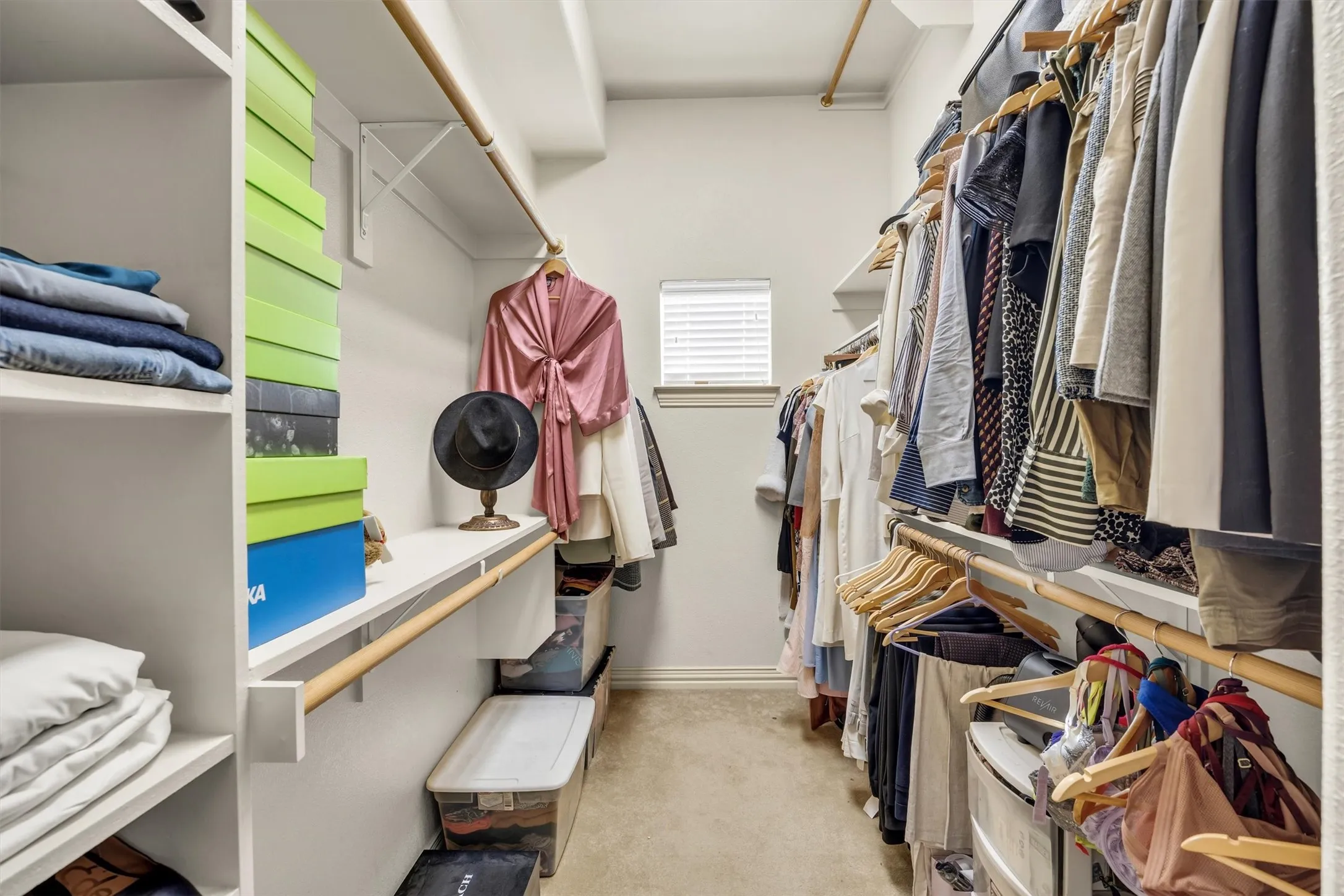 Walk-in closet featuring built-in shelving, multiple hanging rods, and a window with blinds