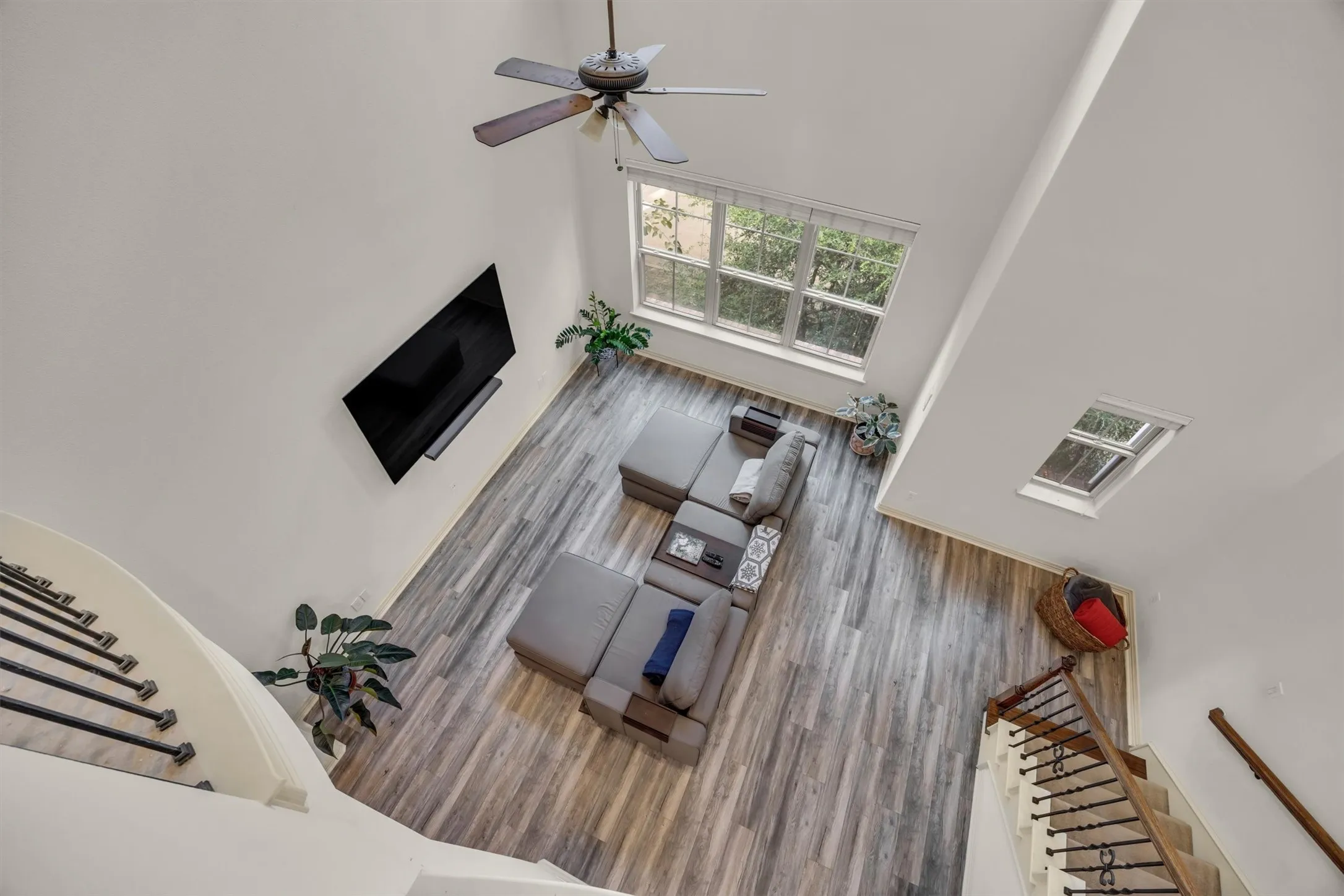 Vaulted ceiling, wood-finish flooring, ceiling fan, large window, and skylight