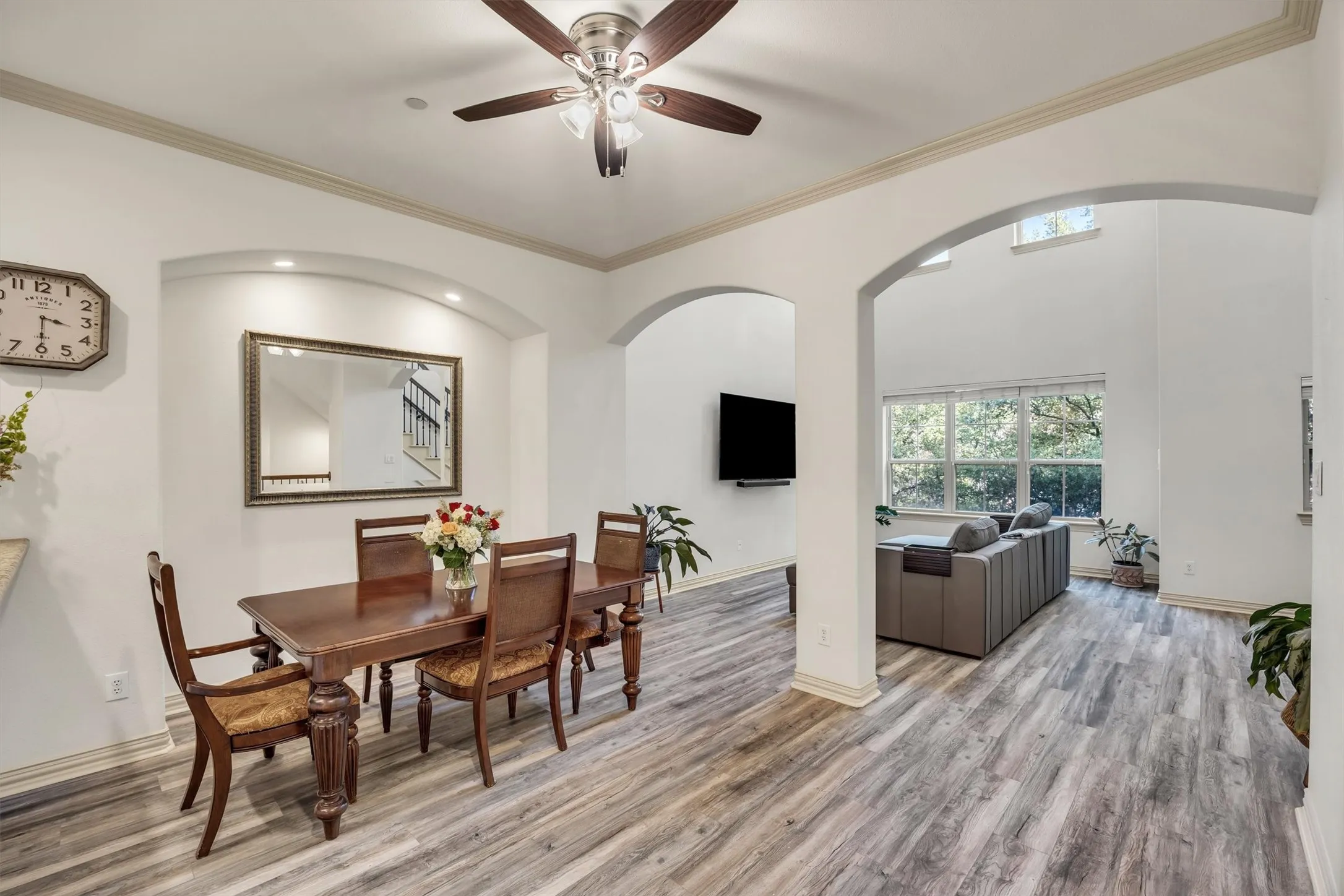 Wood-finish flooring throughout, arched doorways, recessed lighting, ceiling fan, and crown molding