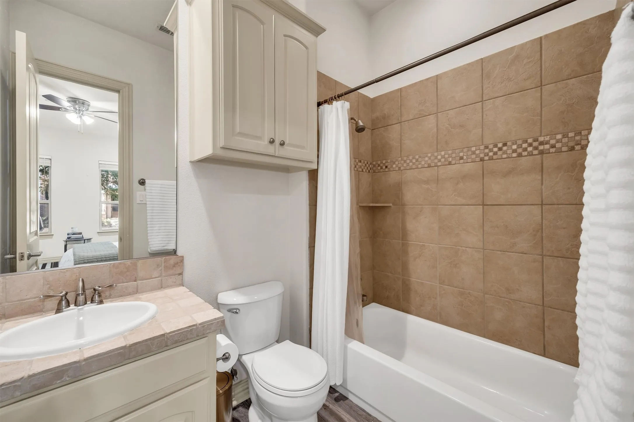 Bathroom featuring a tiled shower surround with accent band, built-in shower niche, and a white tub