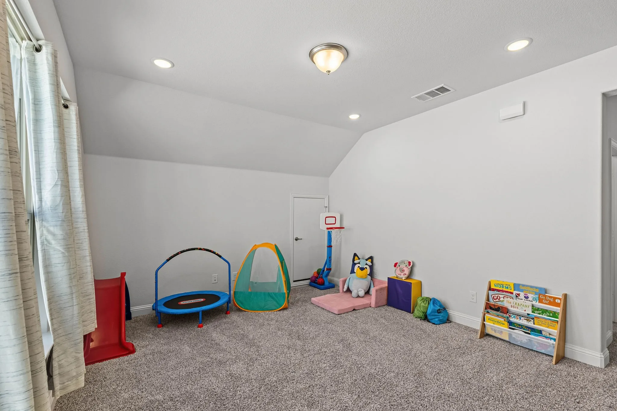 Carpeted room featuring a sloped ceiling, recessed lighting, and a window with vertical blinds