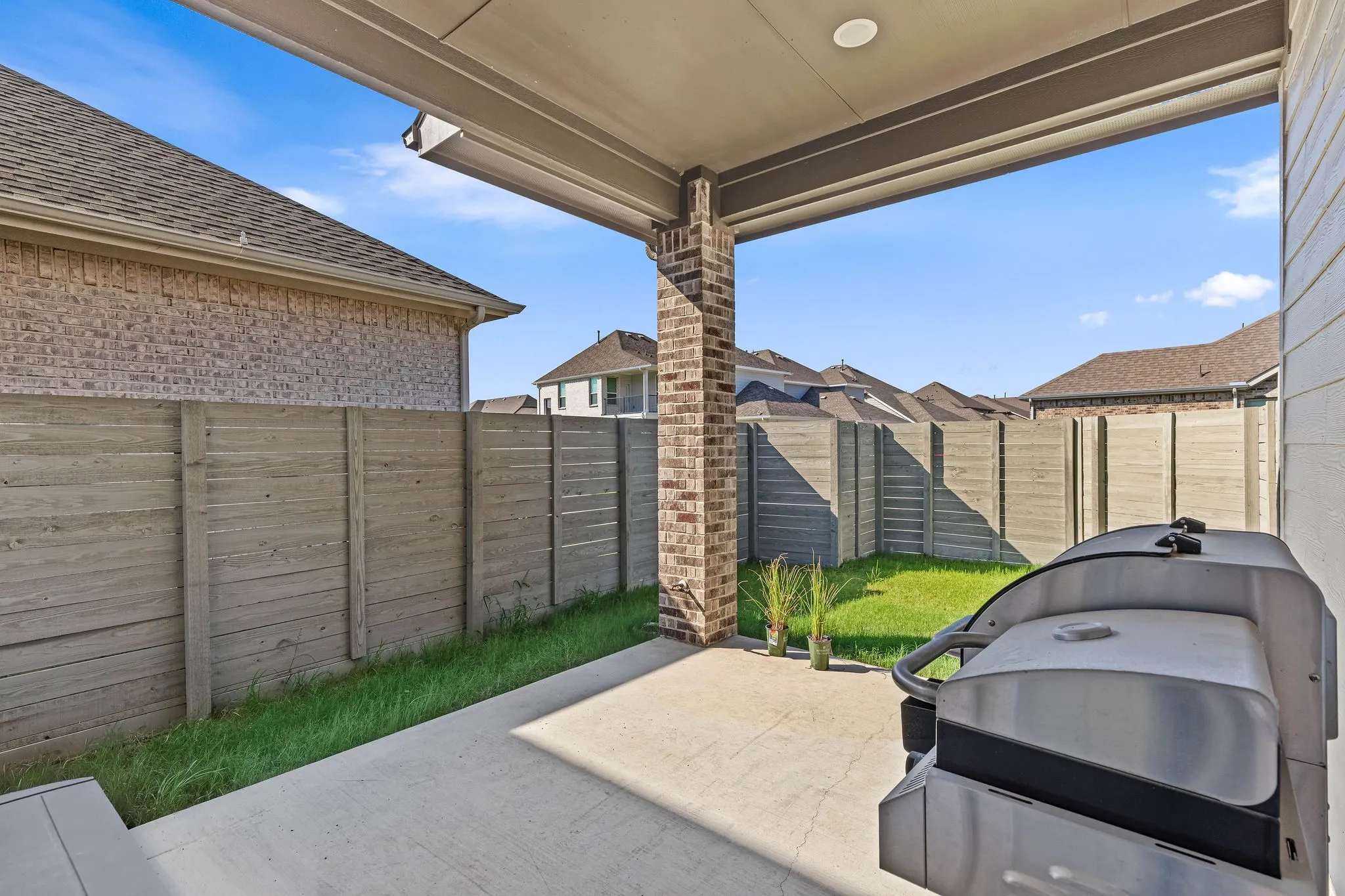 Covered patio with a concrete surface, brick support column, and recessed lighting