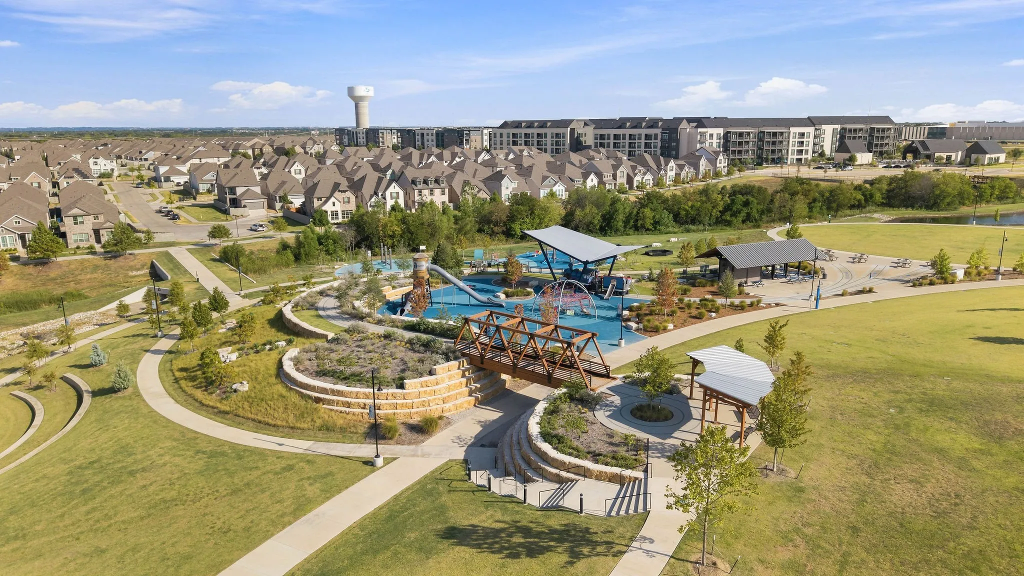 Expansive green spaces with paved pathways, a children's play structure, and covered gathering​​‌​​​​‌​​‌‌​‌‌​​​‌‌​‌​‌​‌​​​‌​​ areas