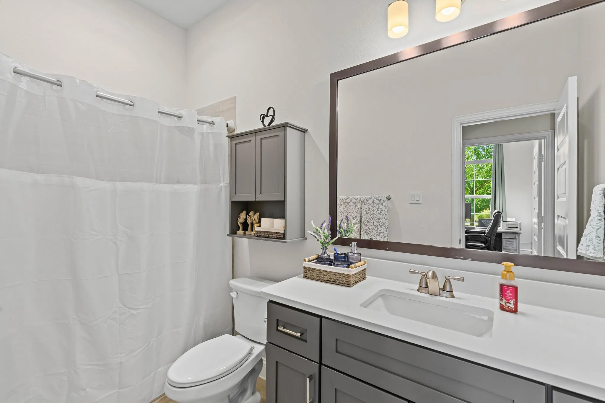 Bathroom featuring a vanity with an undermount sink, a large framed mirror, and a wall-mounted storage cabinet