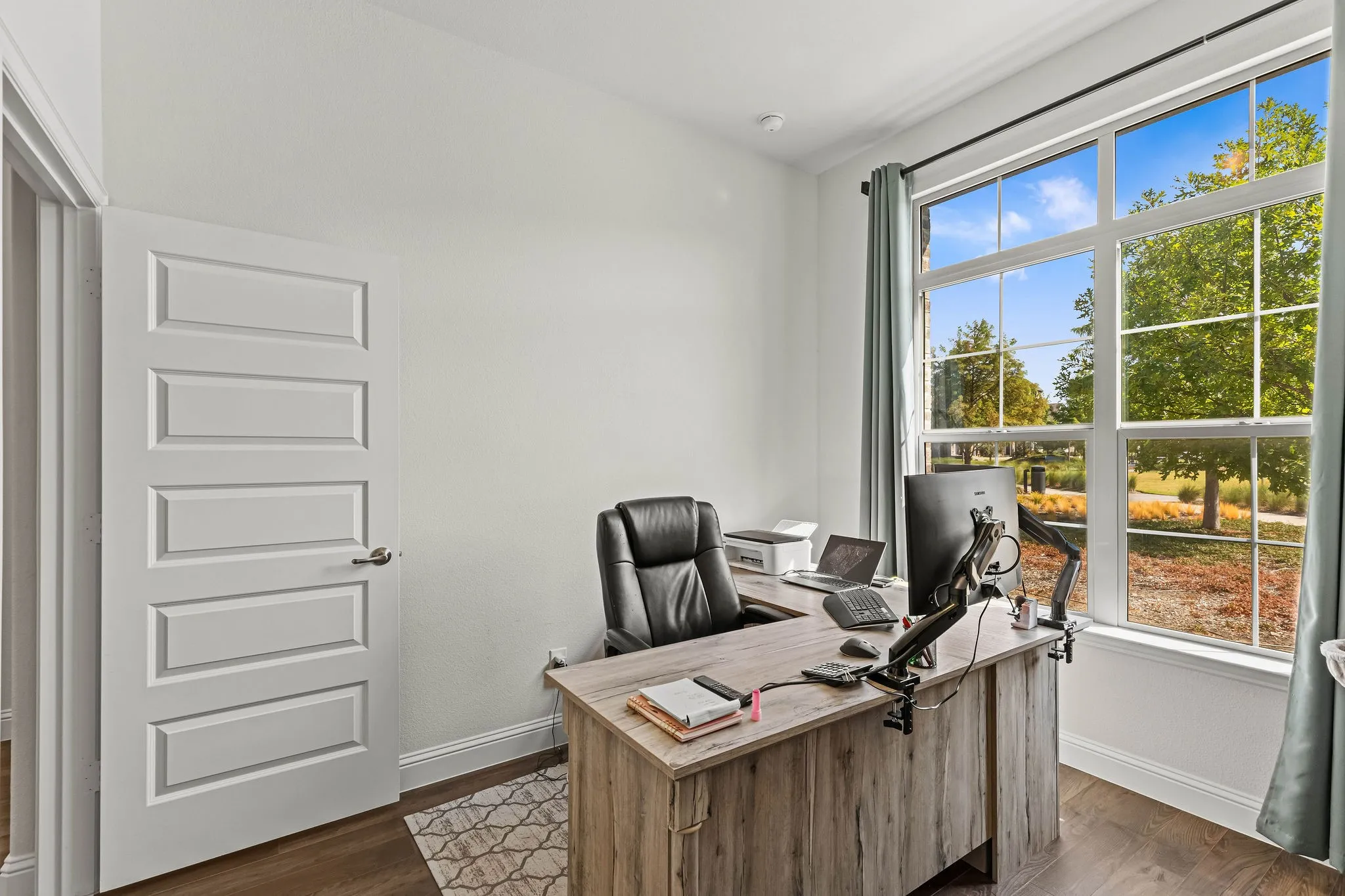 Bright interior with dark wood-finish flooring, white walls, and a large multi-pane window