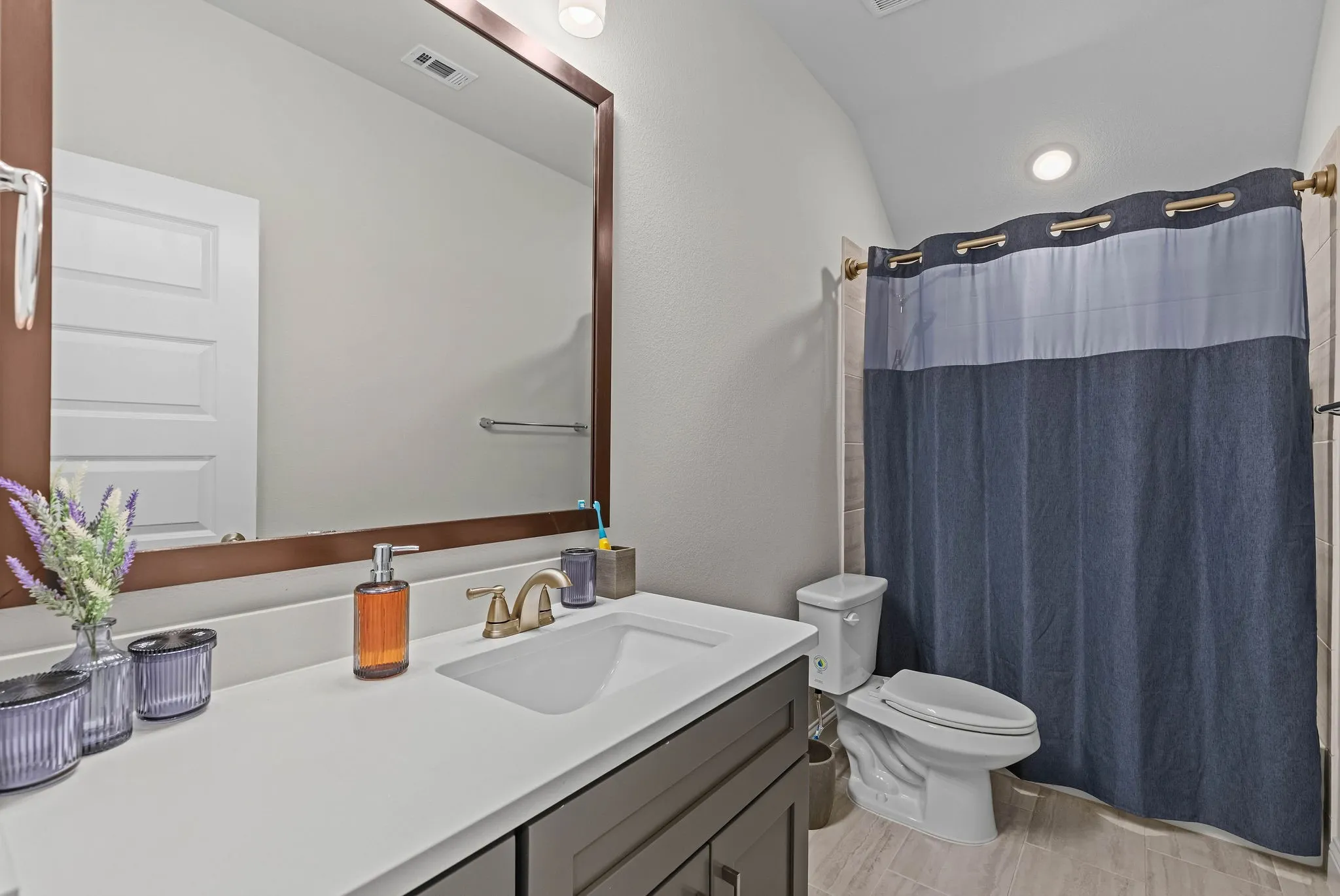 White rectangular undermount sink with a brass-finish faucet, framed mirror, and a built-in vanity with shaker-style cabinetry