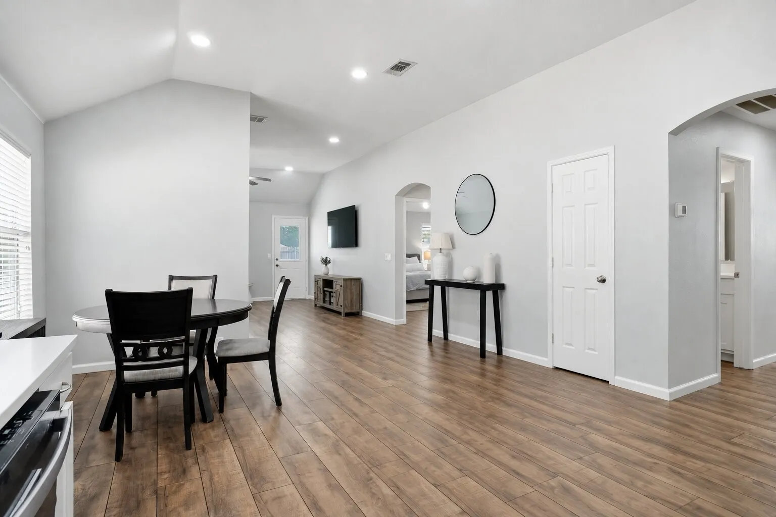 Spacious dining area with vaulted ceilings and continuous wood-look flooring, offering an open flow to the living room and primary bedroom. Photos have been AI enhanced for presentation; no material property features were altered.