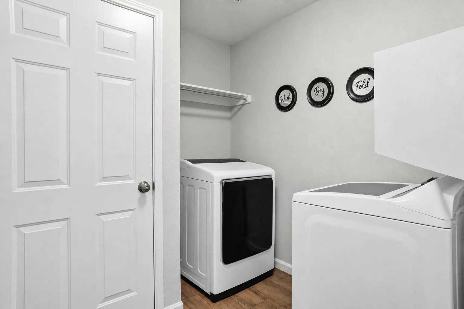 Dedicated laundry room with washer and dryer connections, built-in shelving, and additional storage space. Photos have been AI enhanced for presentation; no material property features were altered.