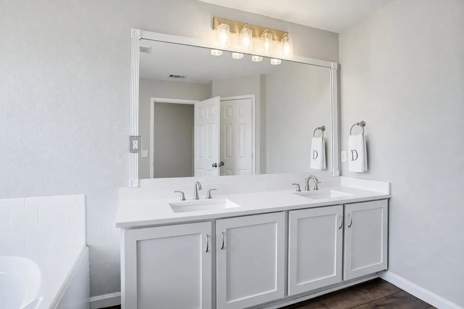 Primary bathroom with a spacious dual-sink vanity, quartz countertop, abundant storage, and an oversized mirror. Photos have been AI enhanced for presentation; no material property features were altered.