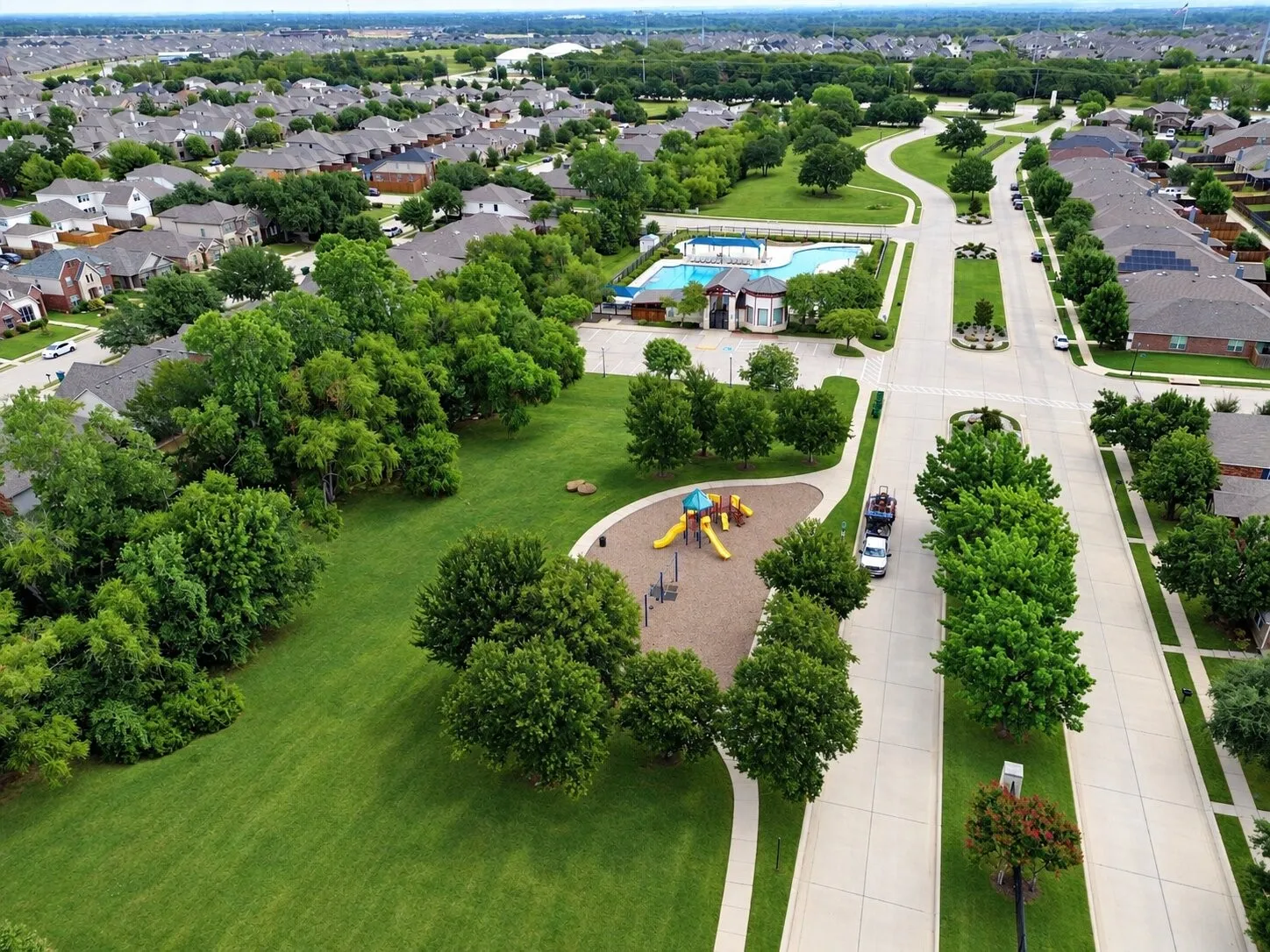 Aerial view of Cross Oak Ranch highlighting its community pool, playground, expansive green spaces, walking trails, and tree-lined neighborhood setting.