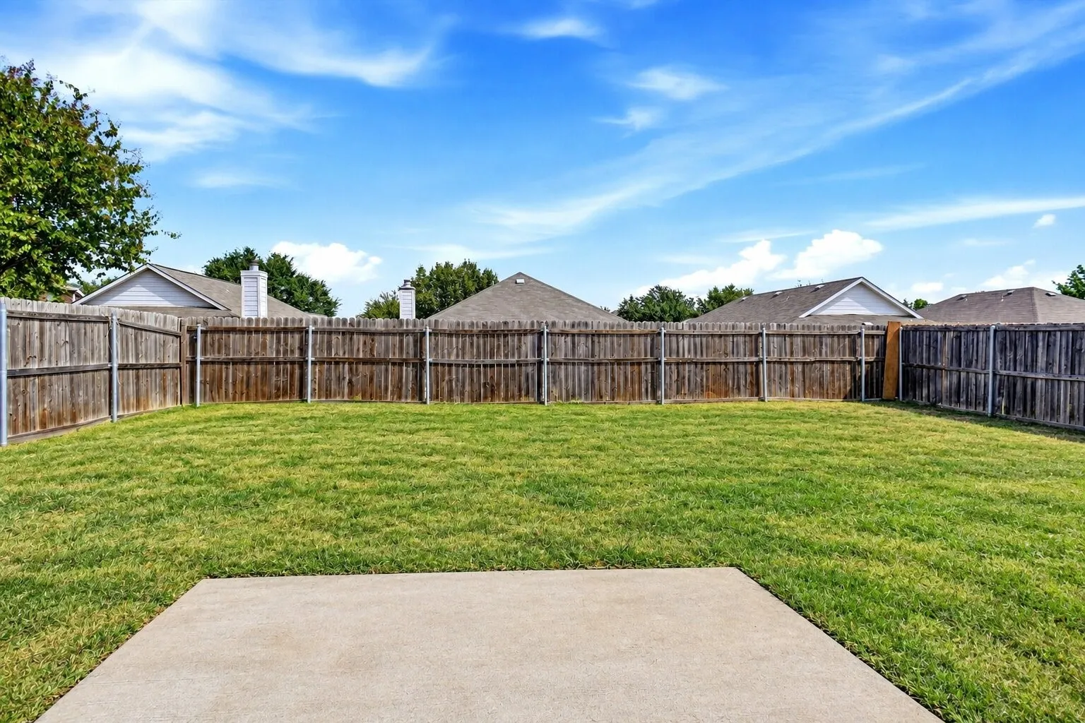 Spacious, fully fenced backyard with a concrete patio and plenty of room for outdoor entertaining, play, or future improvements. Photos have been AI enhanced for presentation; no material property features were altered.