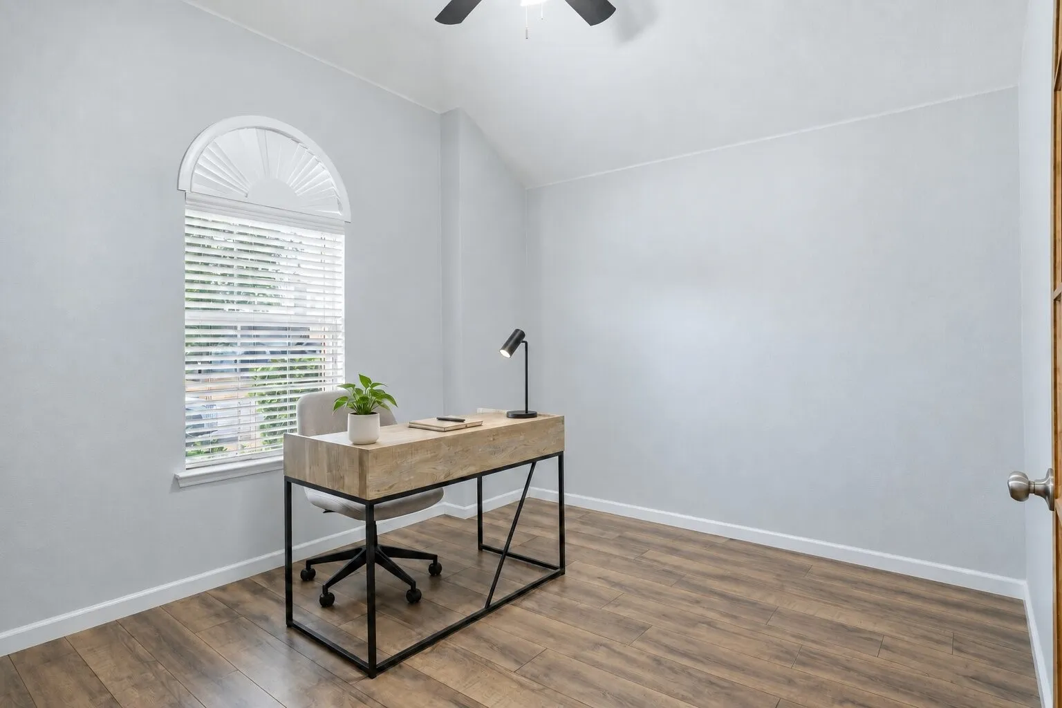 Private home office featuring a vaulted ceiling, abundant natural light, and plenty of space for a comfortable workspace. Photos have been AI enhanced for presentation; no material property features were altered.