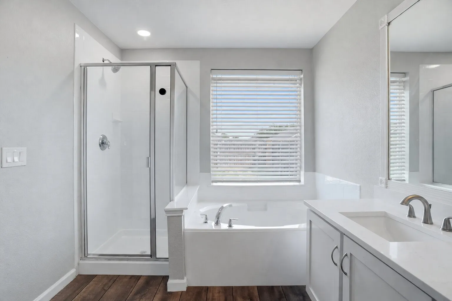 Primary bathroom featuring a soaking tub, separate glass-enclosed shower, quartz-topped vanity, and abundant natural light. Photos have been AI enhanced for presentation; no material property features were altered.