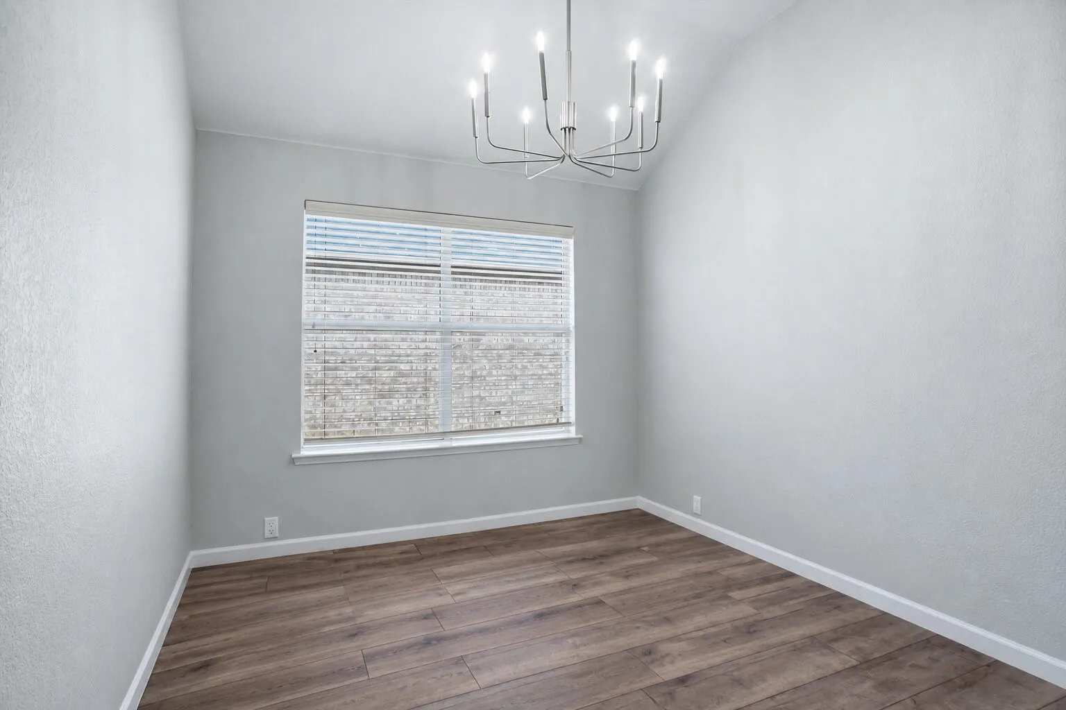 Versatile formal dining room with a vaulted ceiling and modern chandelier—also ideal as a sitting room or second living area. Photos have been AI enhanced for presentation; no material property features were altered.
