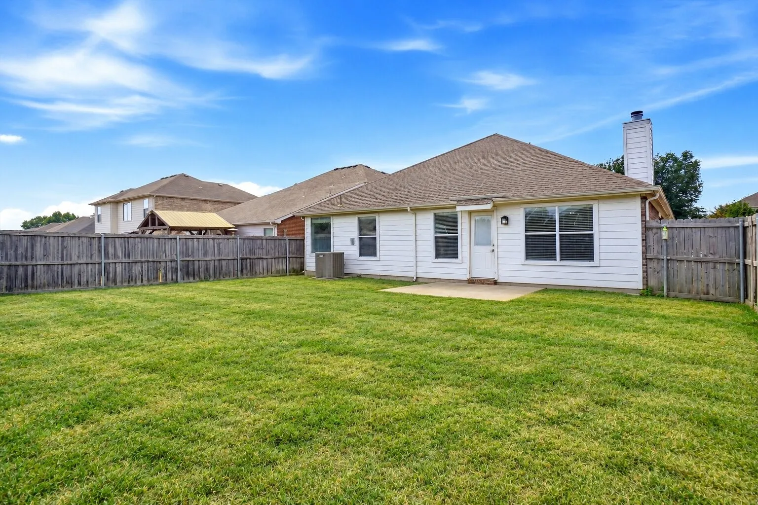 Expansive, fully fenced backyard with a concrete patio and abundant open lawn for entertaining, recreation, pets, or future outdoor additions. Photos have been AI enhanced for presentation; no material property features were altered.