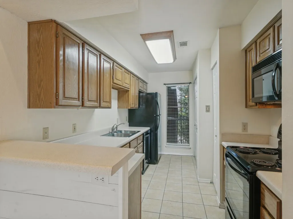 Kitchen featuring wood-finish cabinetry, light-toned countertops, and tile flooring