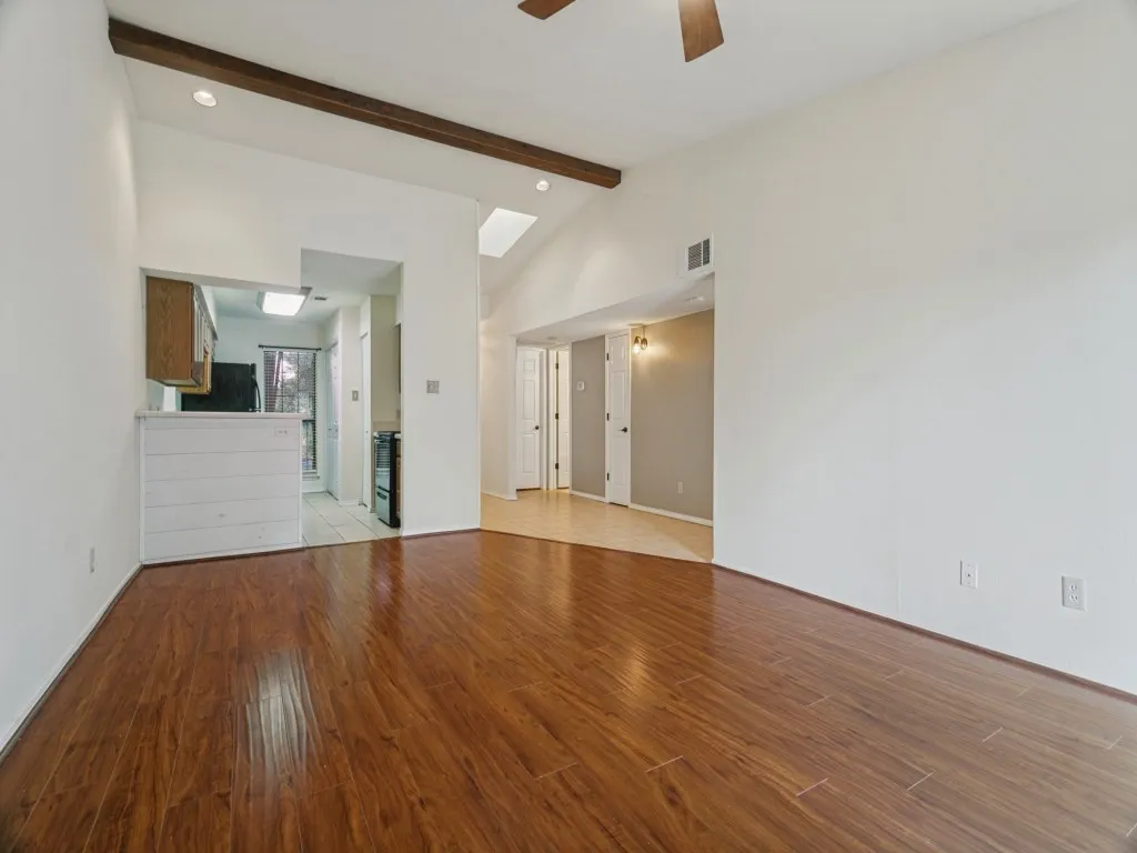 Wood-finish flooring throughout, vaulted ceilings with exposed wood beams, and a skylight providing natural illumination