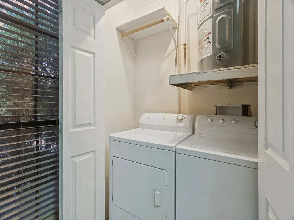 Laundry area featuring a built-in shelf with water heater, an additional wall-mounted shelf, and panel doors