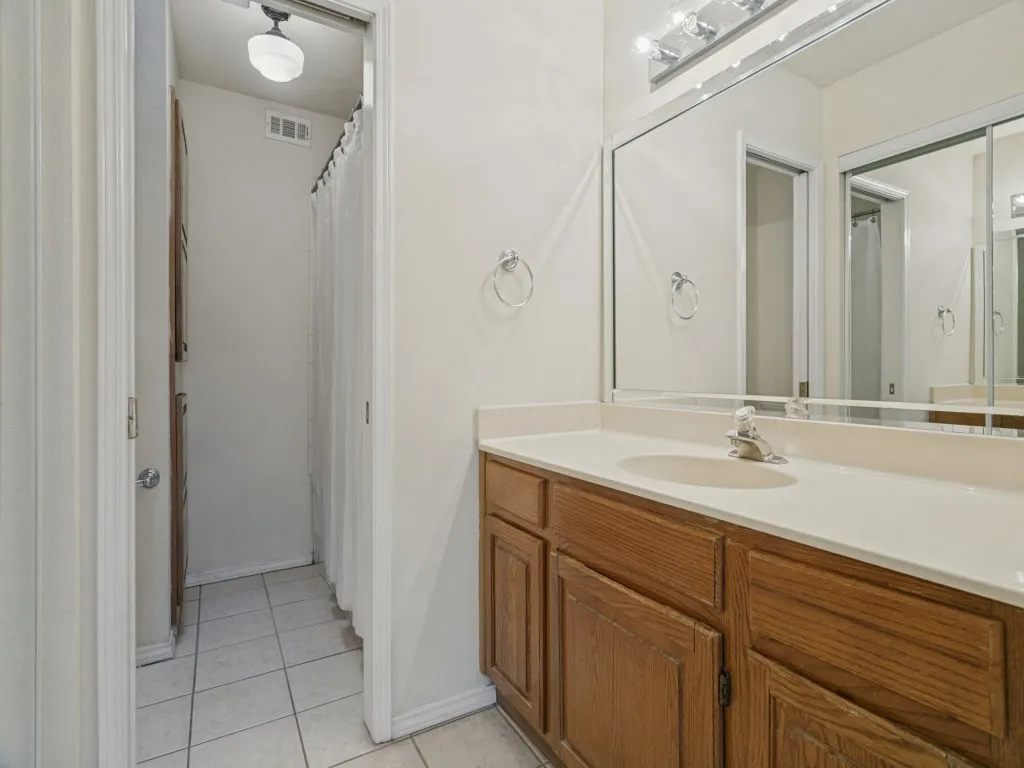 Bathroom featuring a vanity with wood-finish cabinetry, a light-colored countertop, and a large wall-mounted mirror