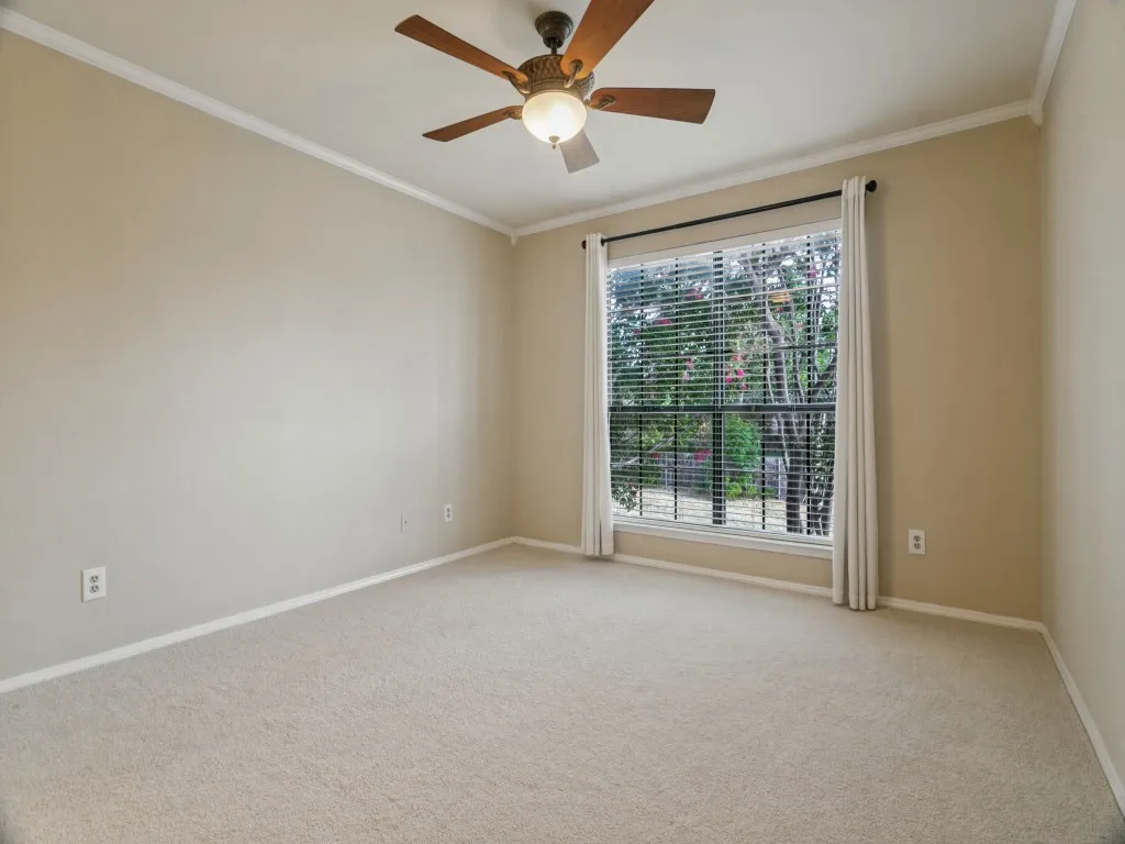 Wall-to-wall carpeting, crown molding, and a ceiling fan with integrated lighting