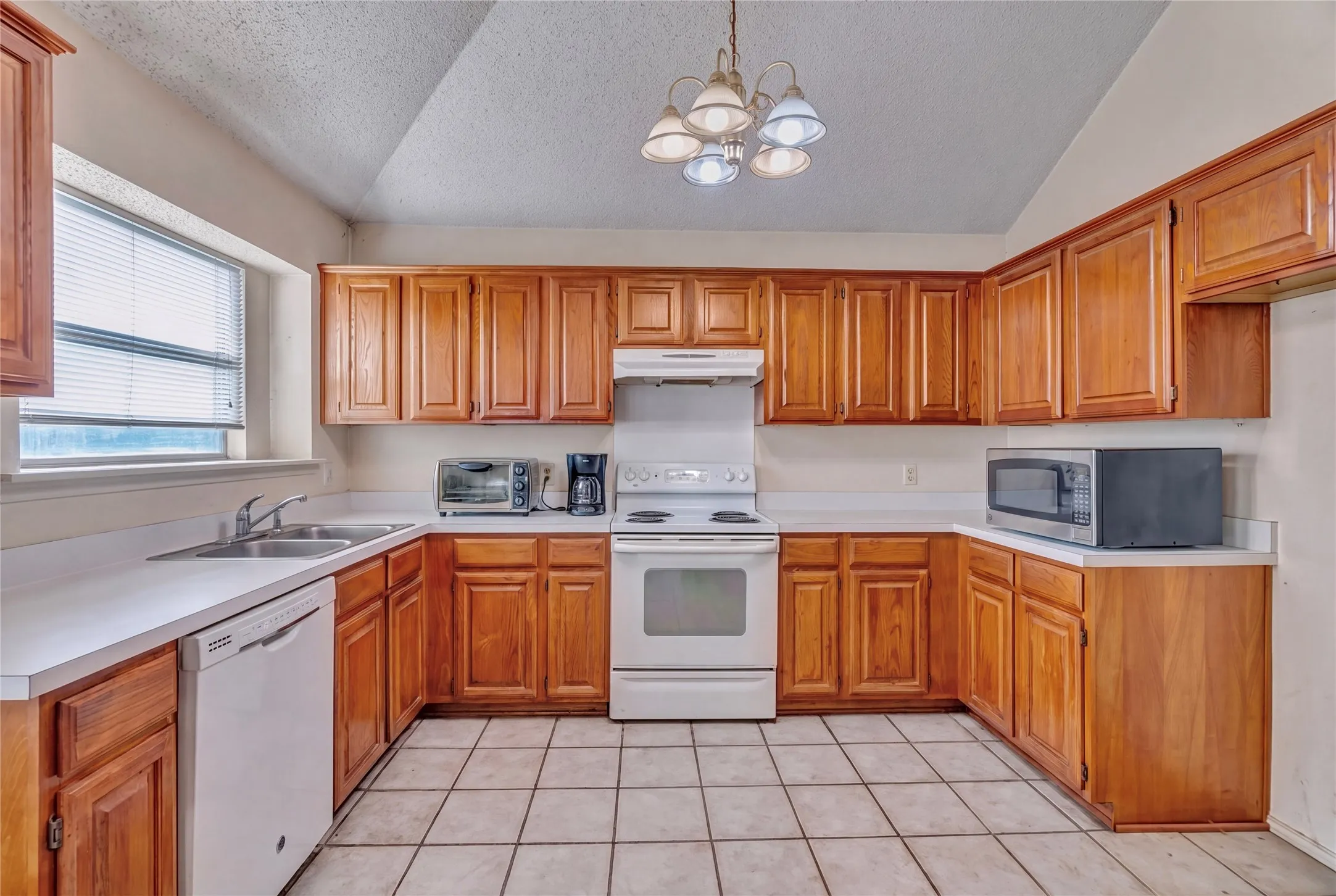 Kitchen featuring wood cabinetry, white countertops, tile flooring, and a stainless steel double sink