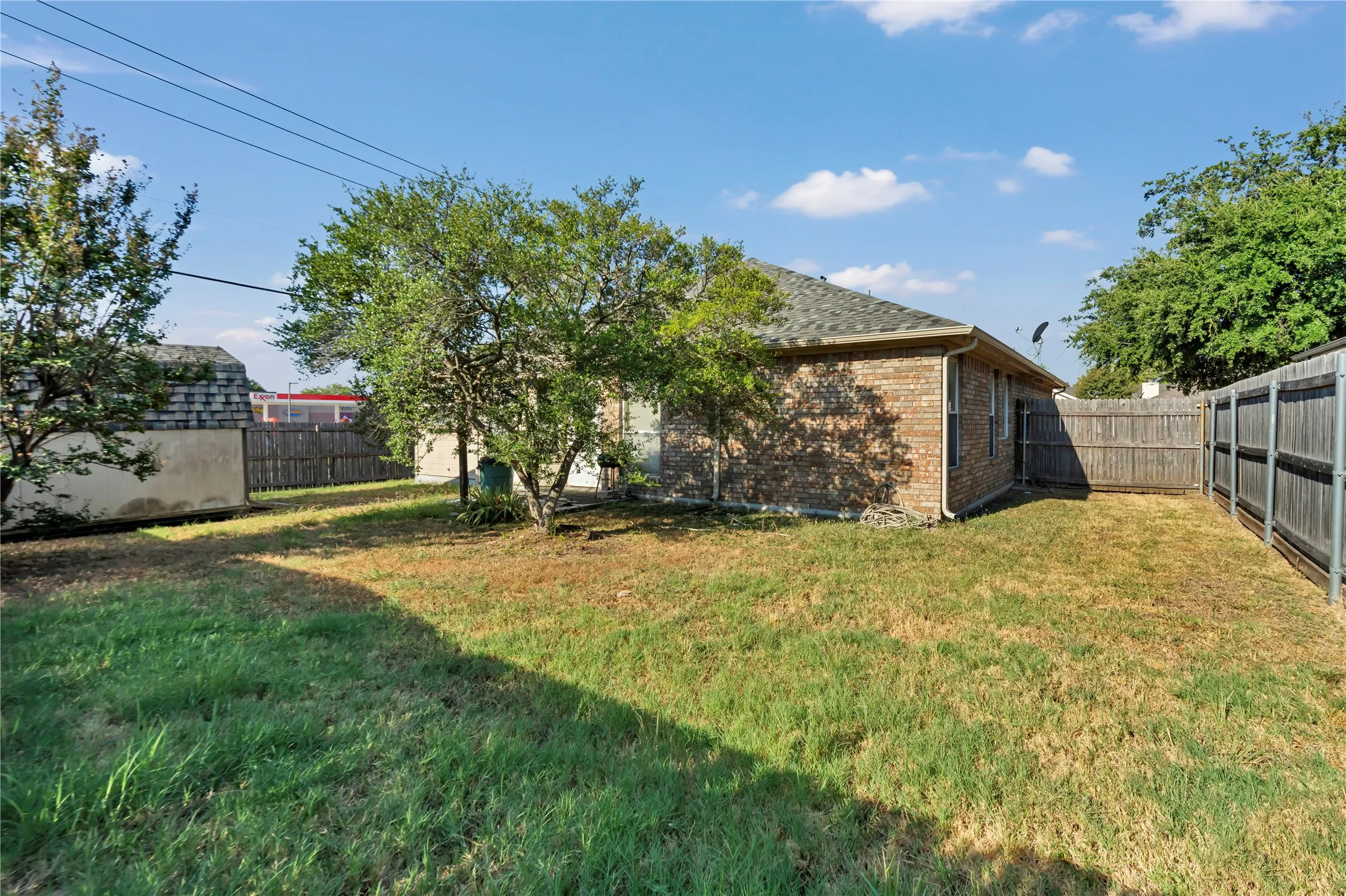 Expansive backyard featuring mature trees, a wood privacy fence, and brick exterior