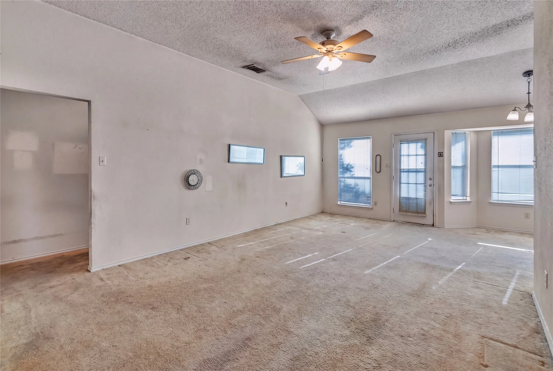 Vaulted ceiling with an attached ceiling fan, multiple windows, and a glass-paneled exterior door