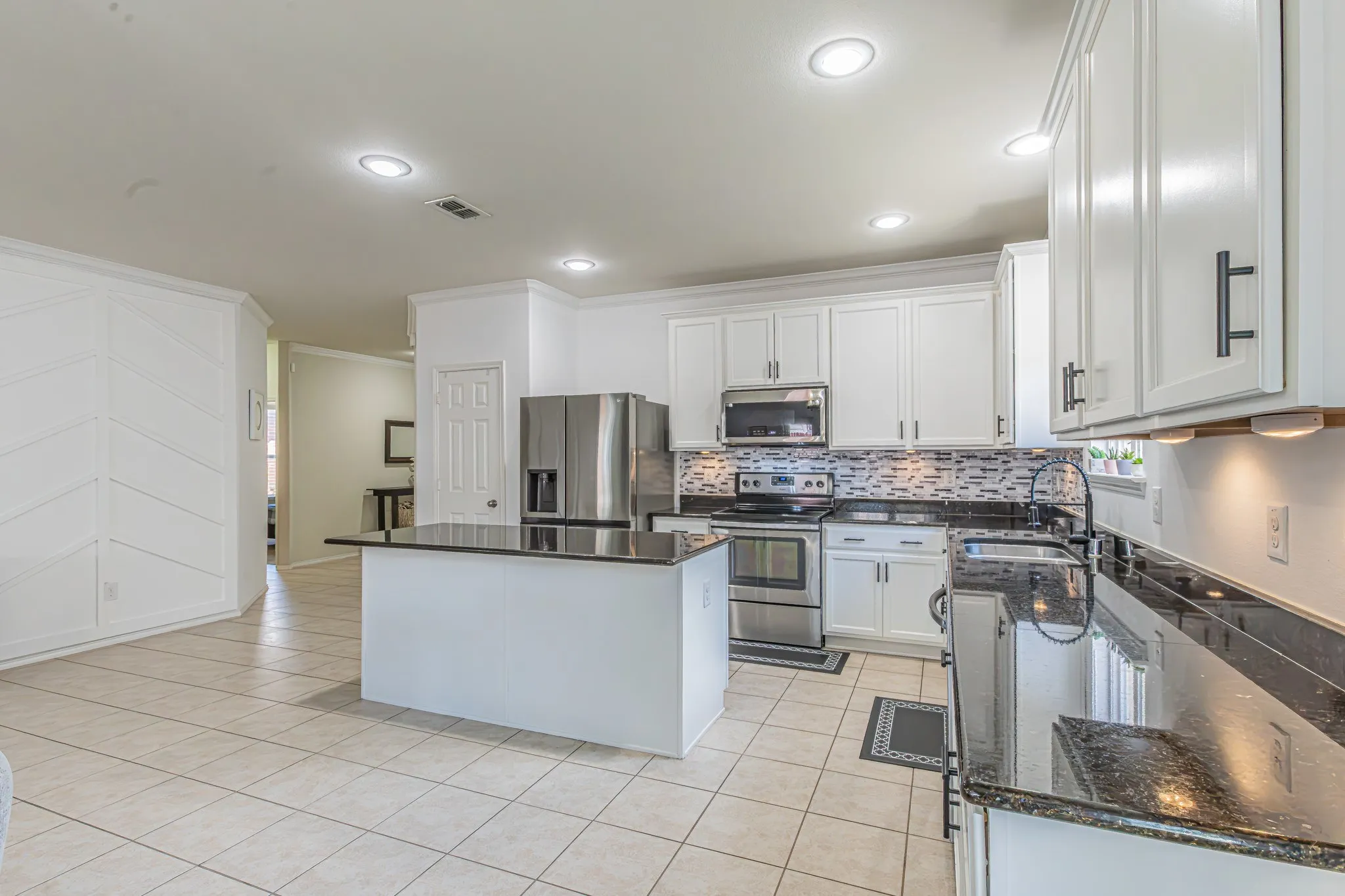 View from dining area towards kitchen, entry hall, and secondary bedrooms.