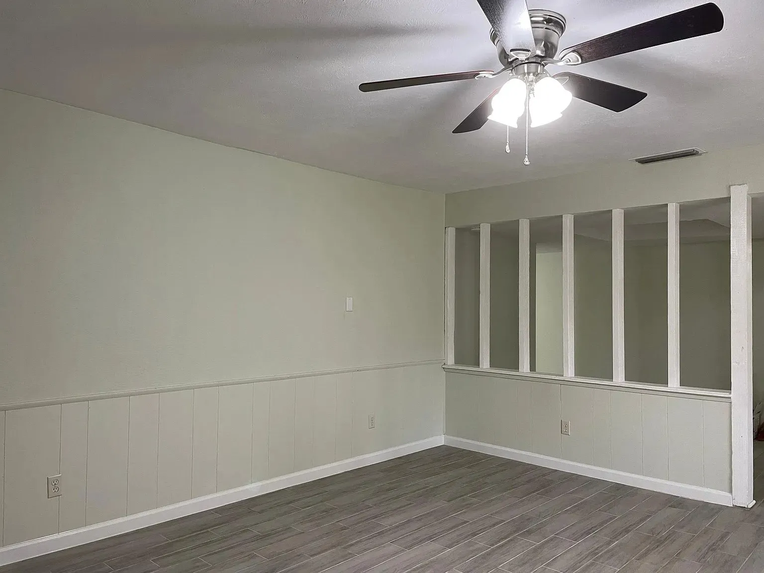 Recessed lighting, wood-finish flooring, wainscoting, and an integrated ceiling fan with lighting