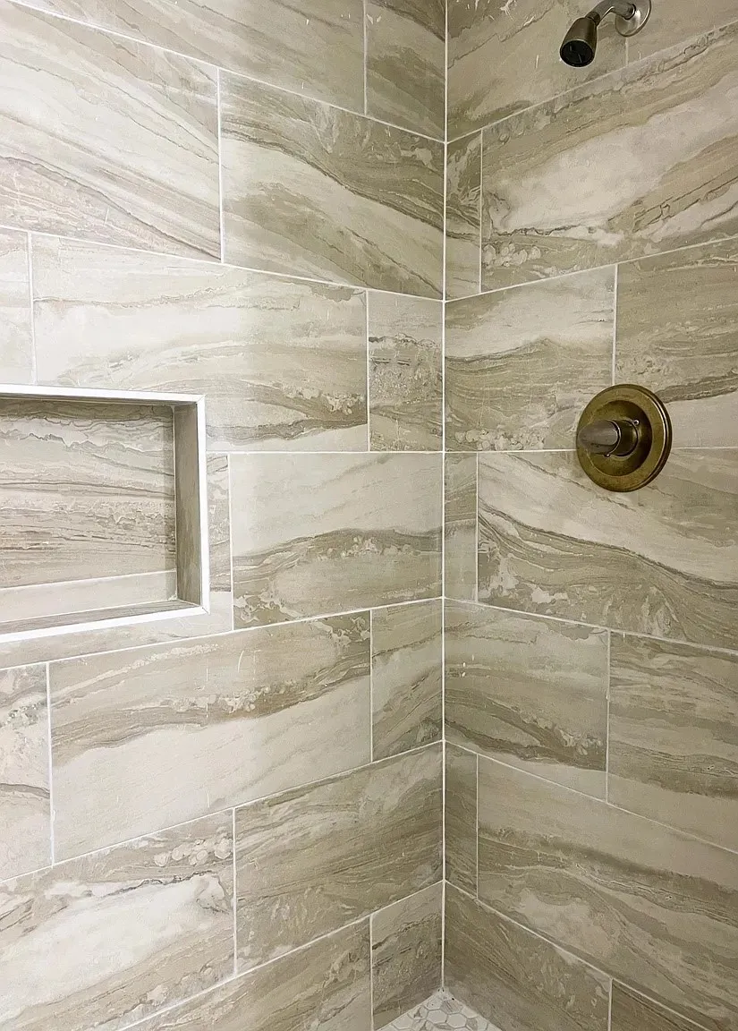 Tiled shower with a built-in niche, featuring a bronze showerhead and control