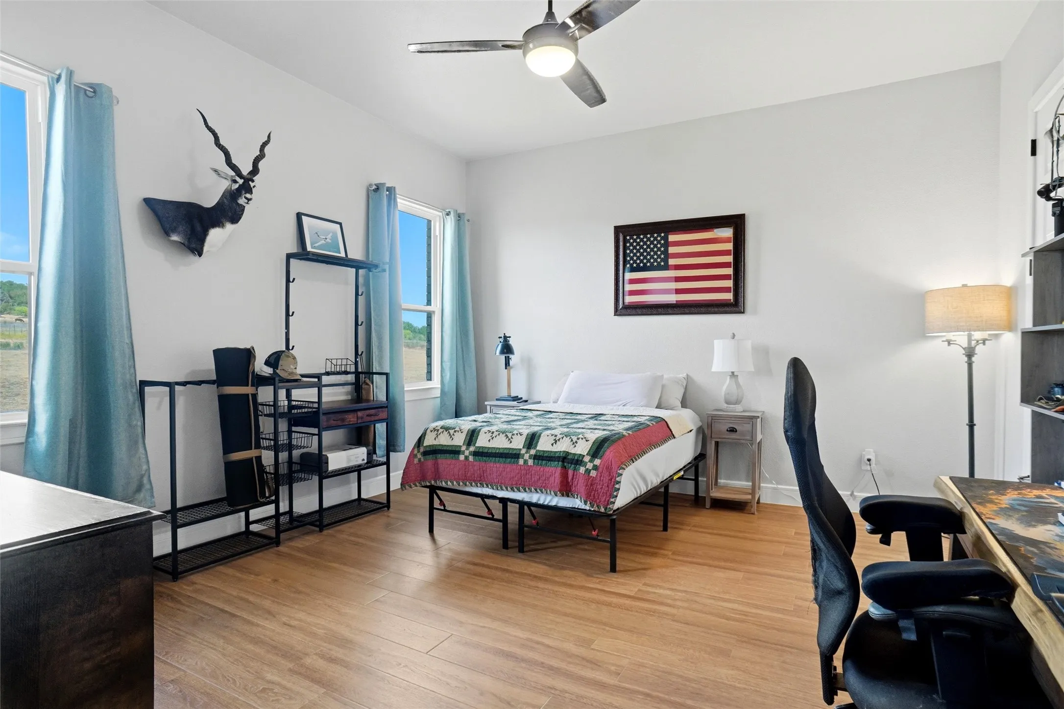 Room featuring wood-finish flooring, white walls, and a ceiling fan with integrated lighting