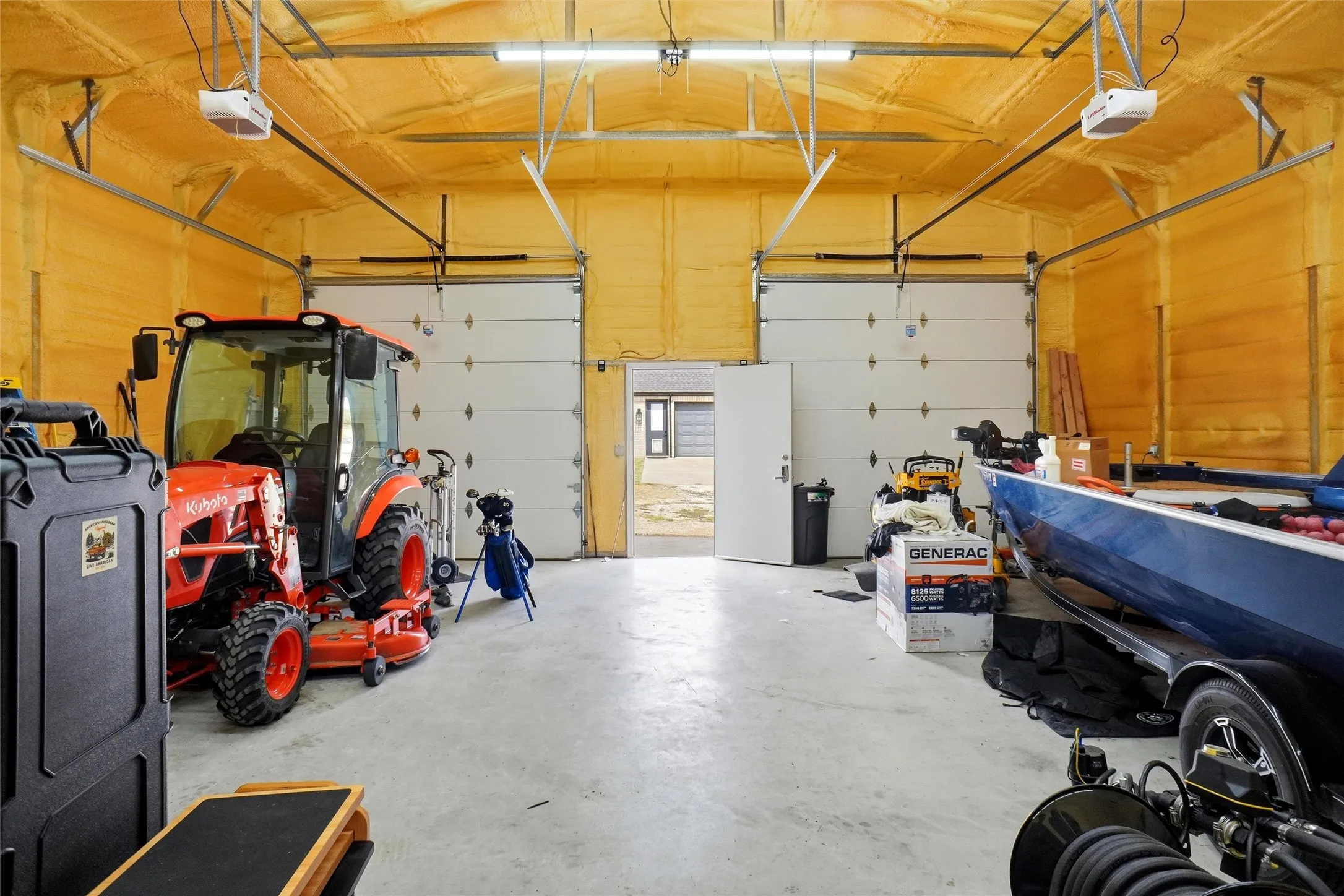 Spacious garage with concrete flooring, two overhead garage doors, and spray foam insulation