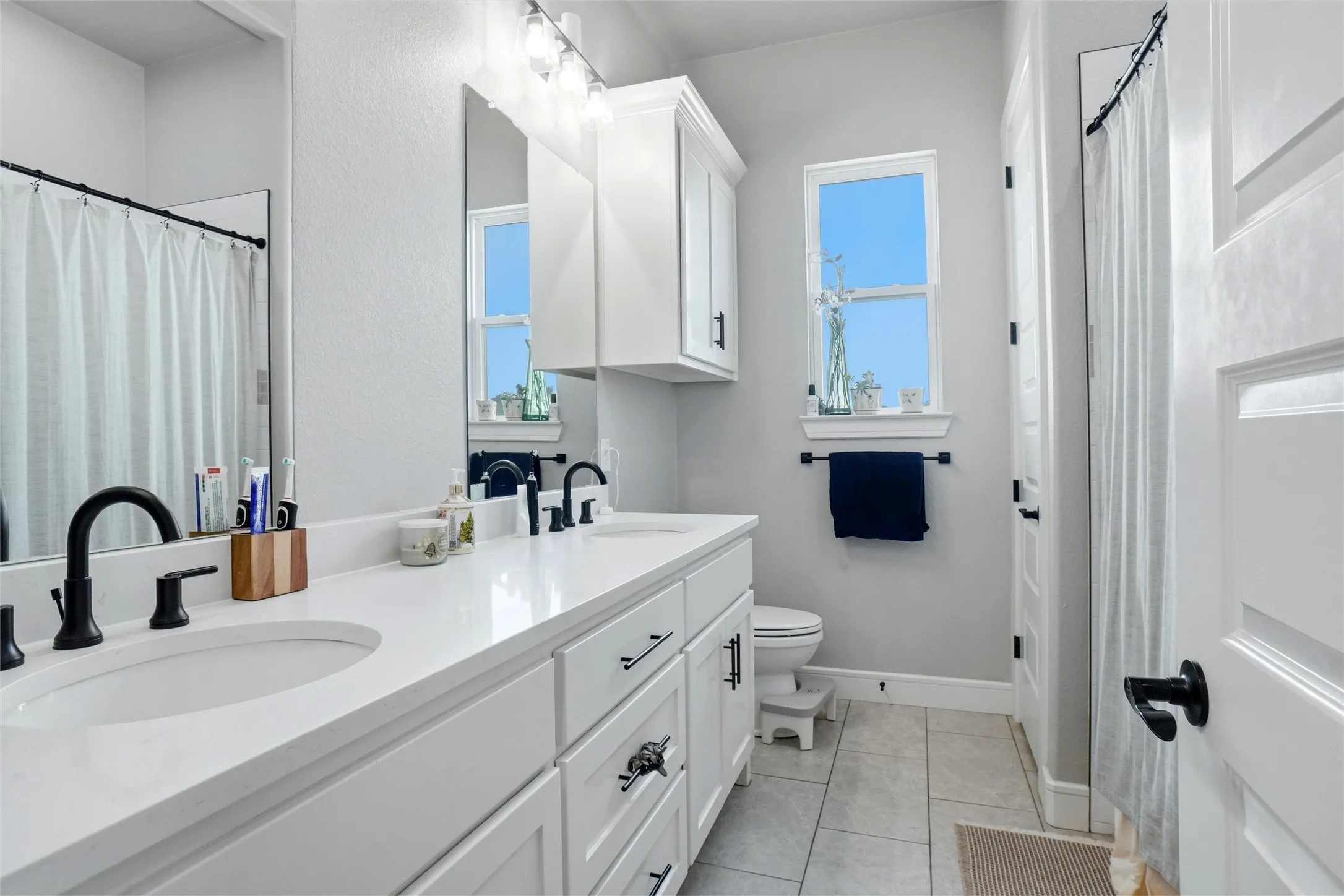 Dual vanity with undermount sinks, white cabinetry, and matte black fixtures