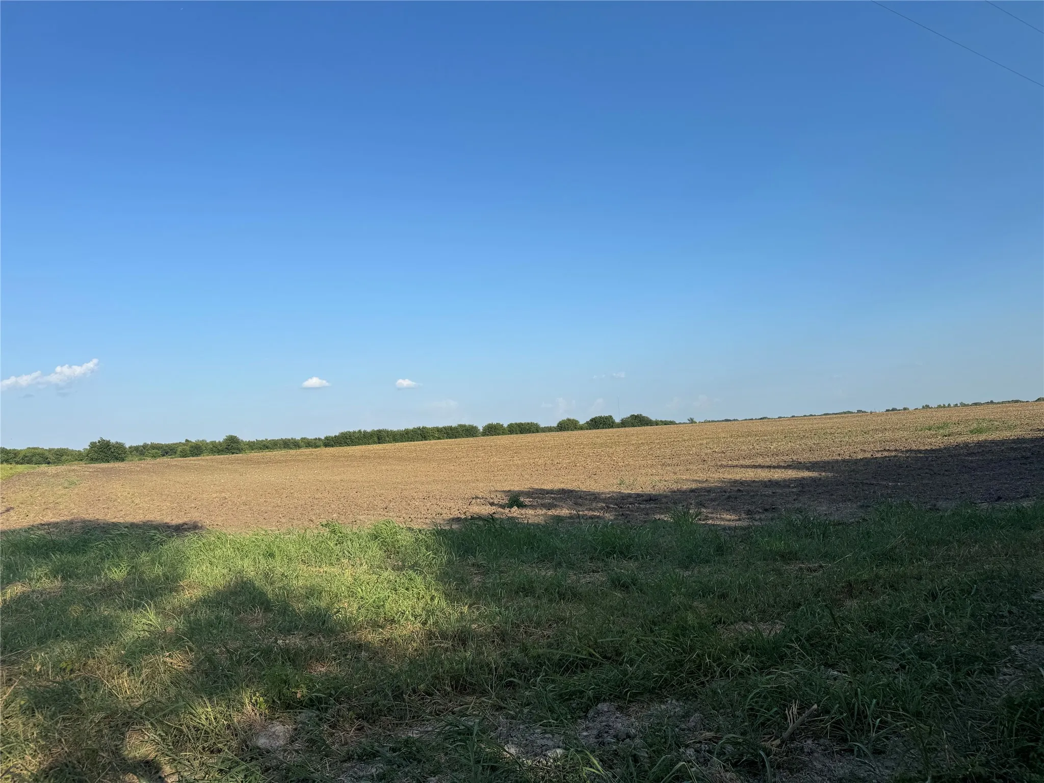 Expansive land parcel featuring clear skies and distant tree lines
