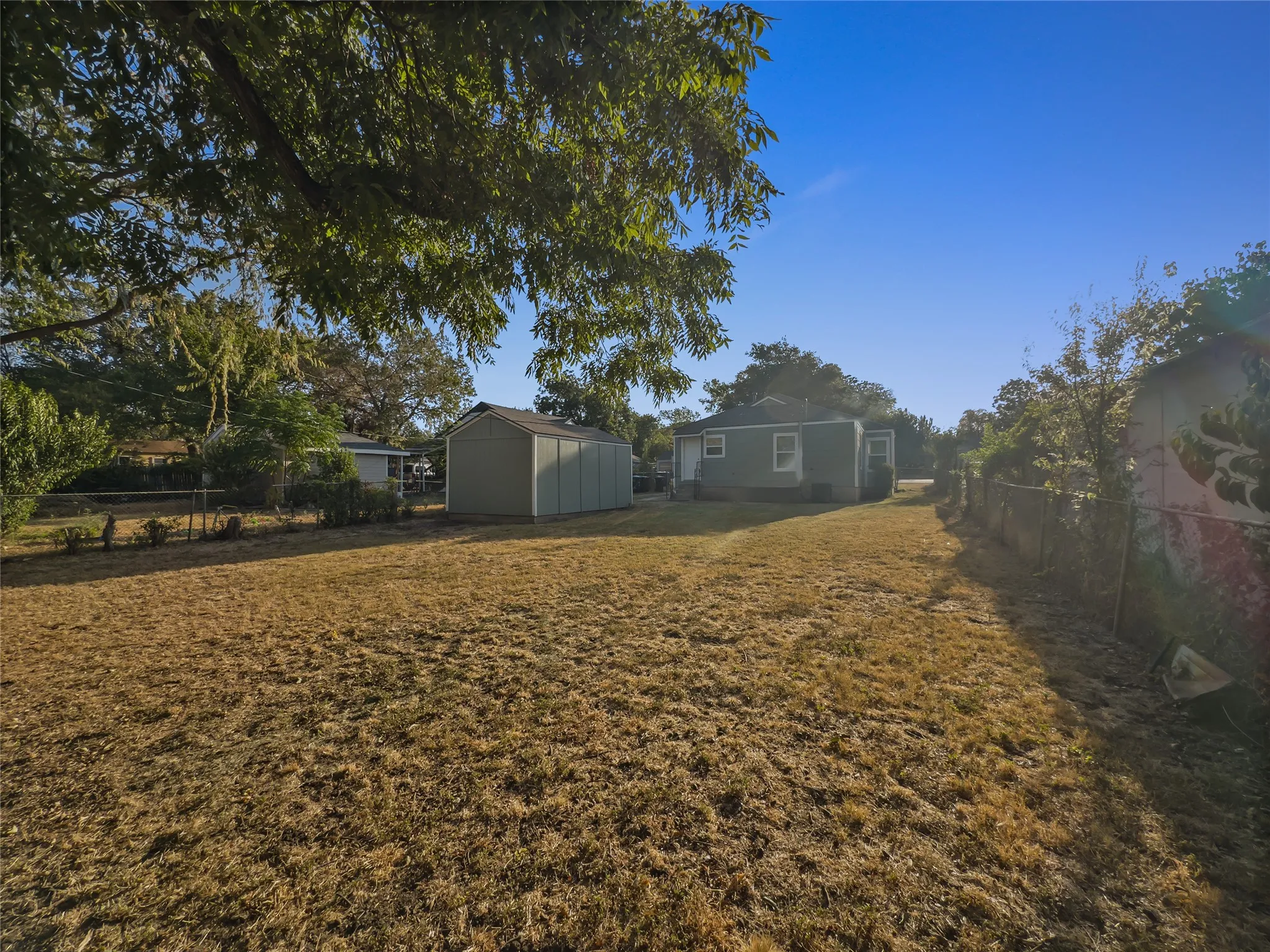 Expansive lawn area with a detached storage shed and mature trees