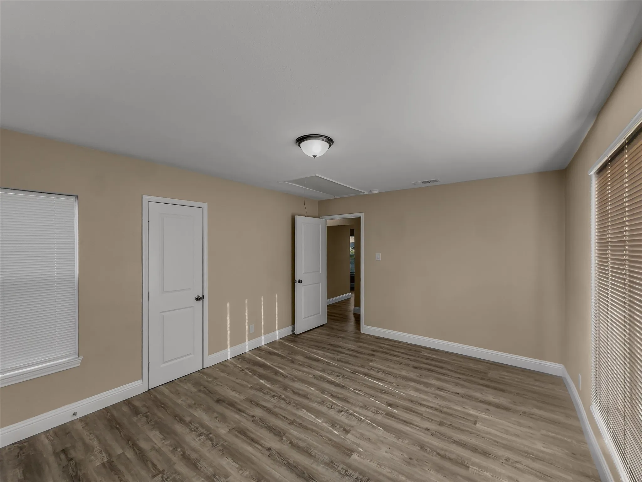 Wood-finish flooring, neutral wall tones, two paneled doors, and ceiling-mounted light fixture