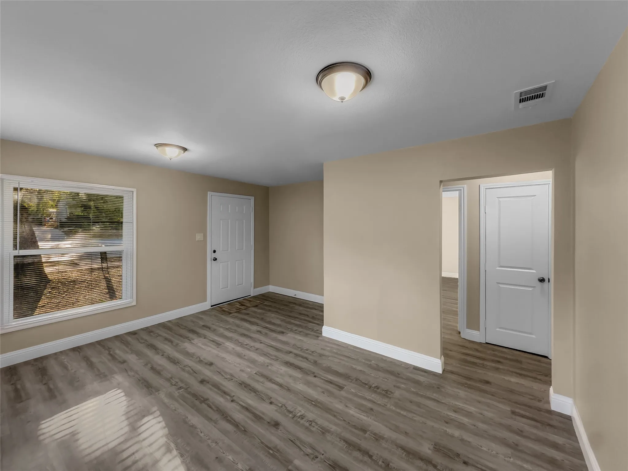 Wood-finish flooring throughout, neutral paint palette, white trim, and a paneled entry door