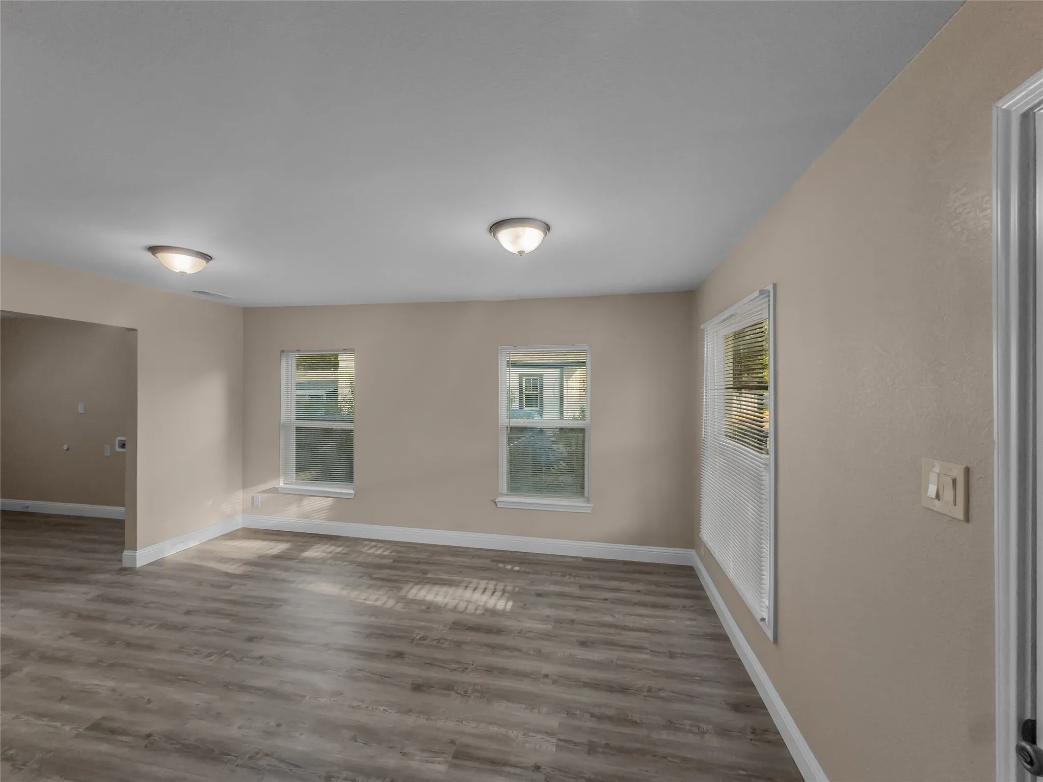 Wood-finish flooring, multiple windows, neutral wall tones, and recessed lighting
