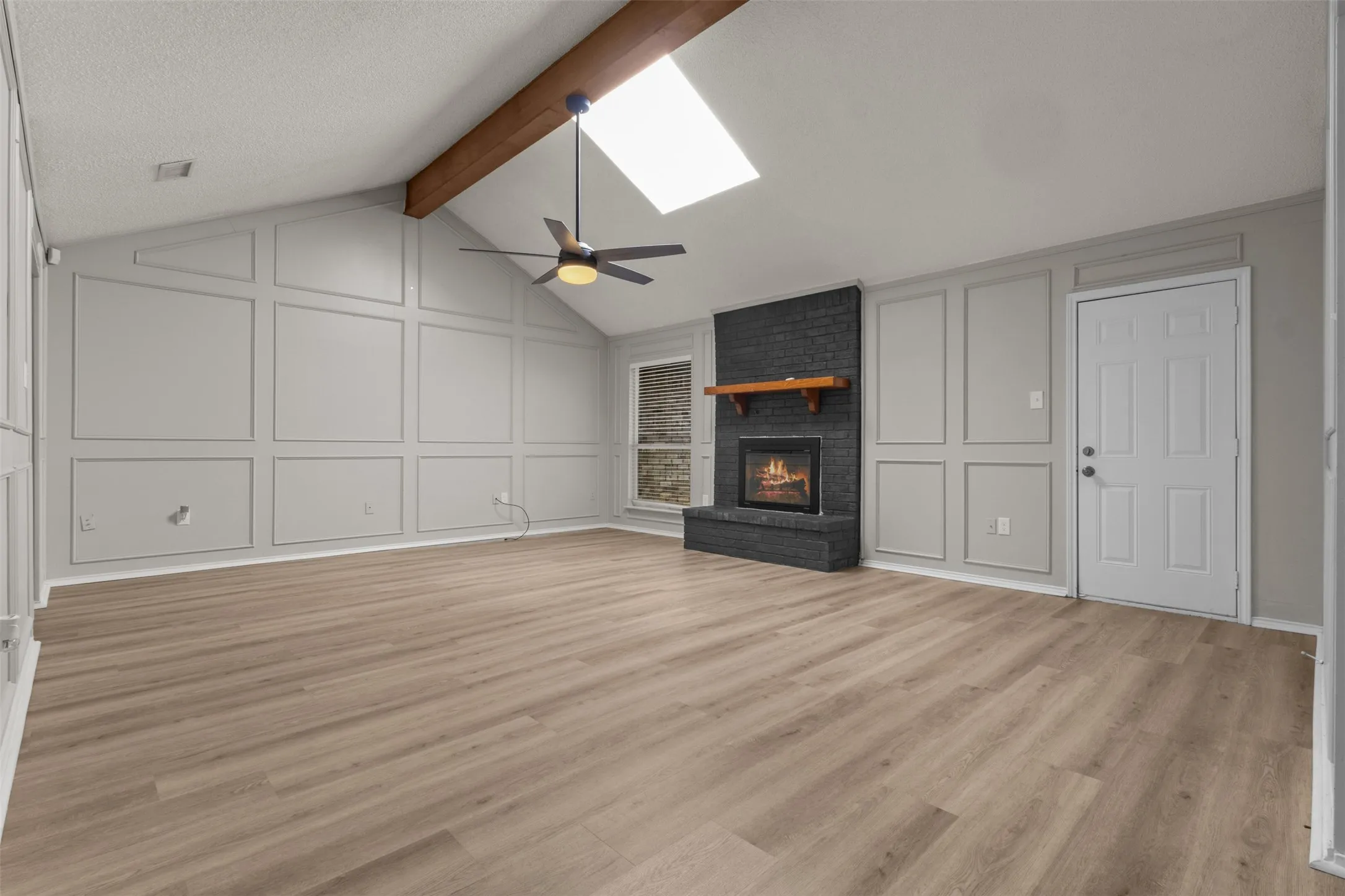 Vaulted ceiling with exposed wood beam, skylight, and ceiling fan