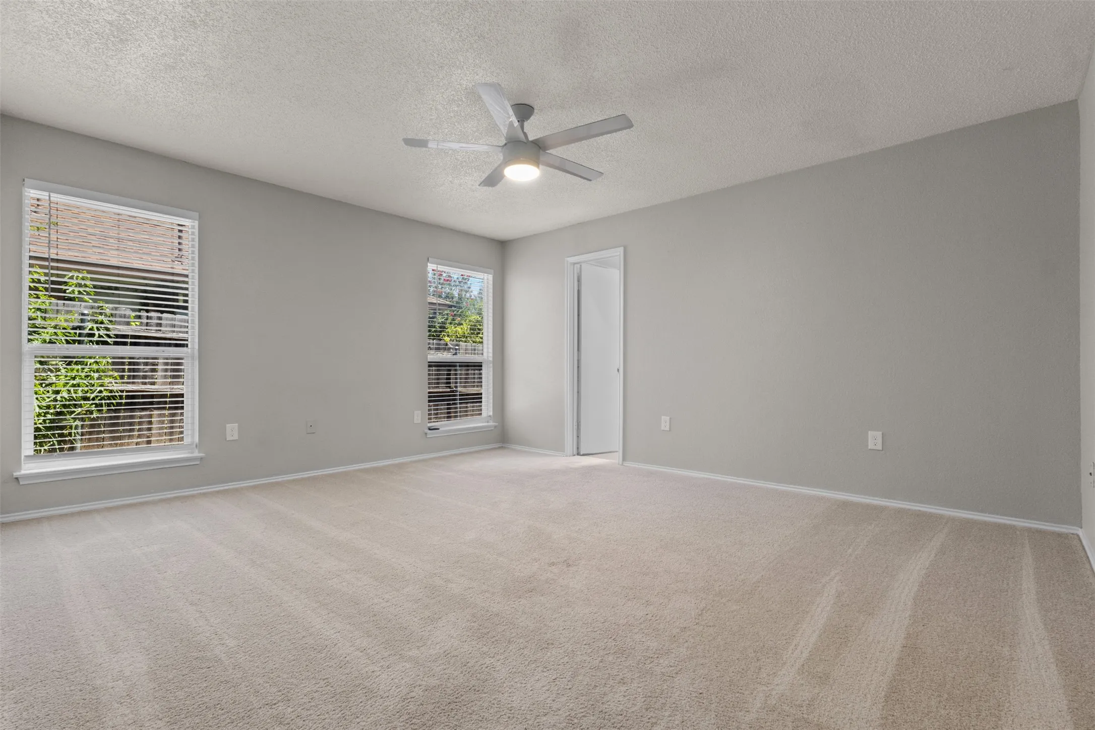 Carpeted room with two windows, a ceiling fan, and a closet with bifold doors