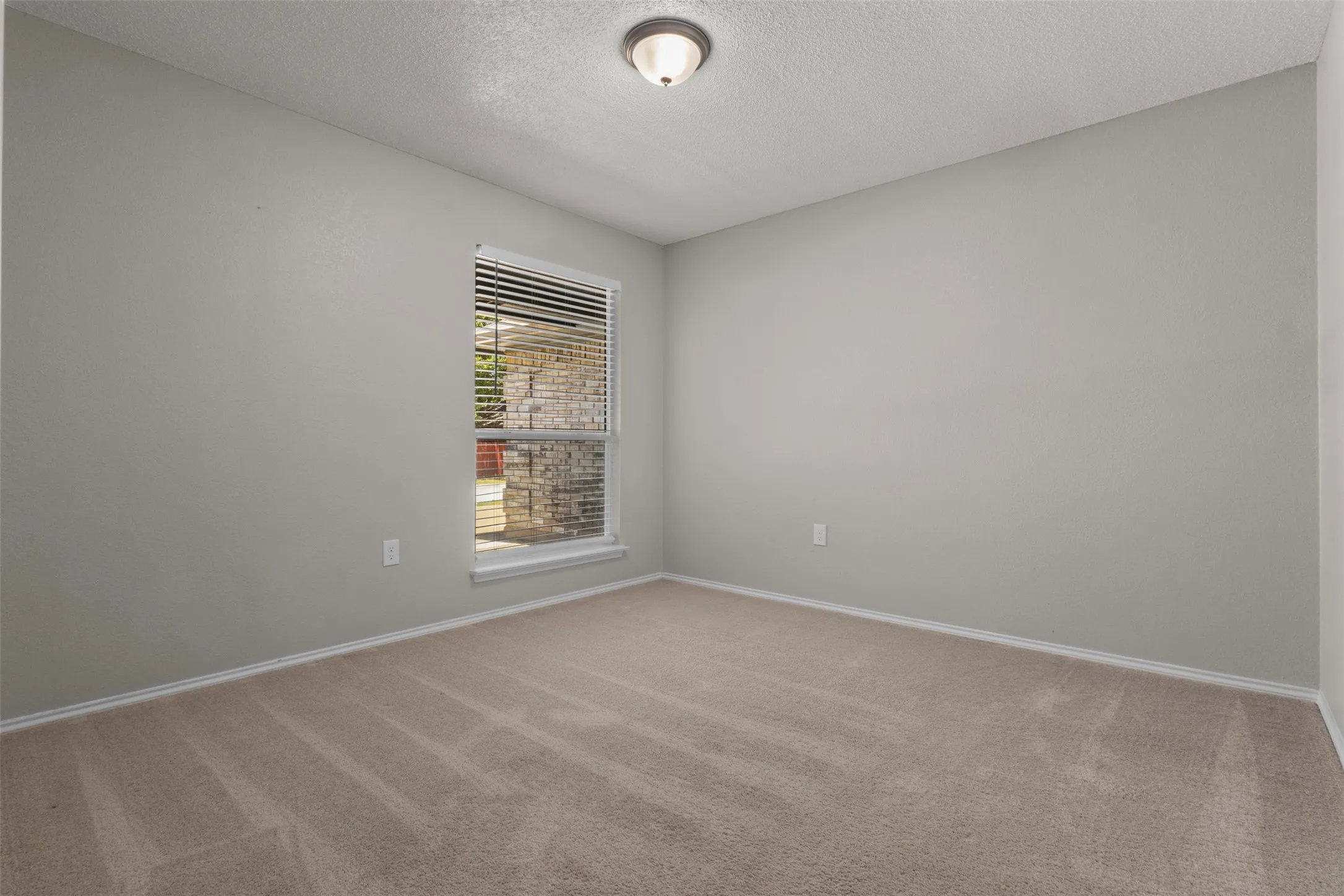 Neutral tone walls with an overhead flush-mount light fixture