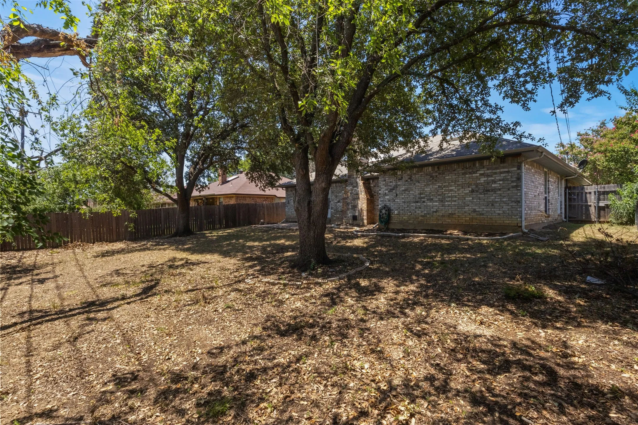 Expansive rear yard featuring mature trees and a wood privacy fence