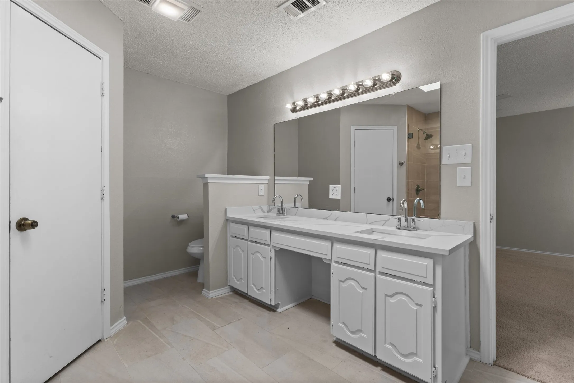 Double vanity with integrated sinks, white cabinetry, and a large wall-mounted mirror