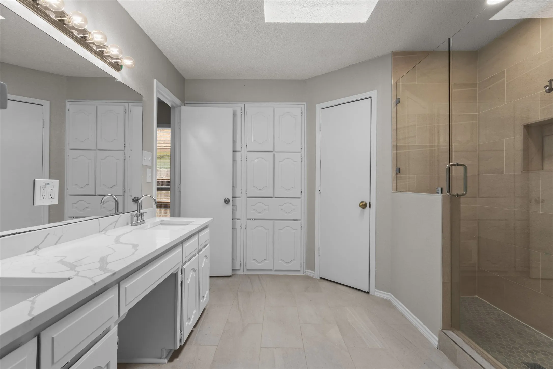Dual vanity with a white countertop, built-in cabinetry, and a walk-in shower with a glass enclosure