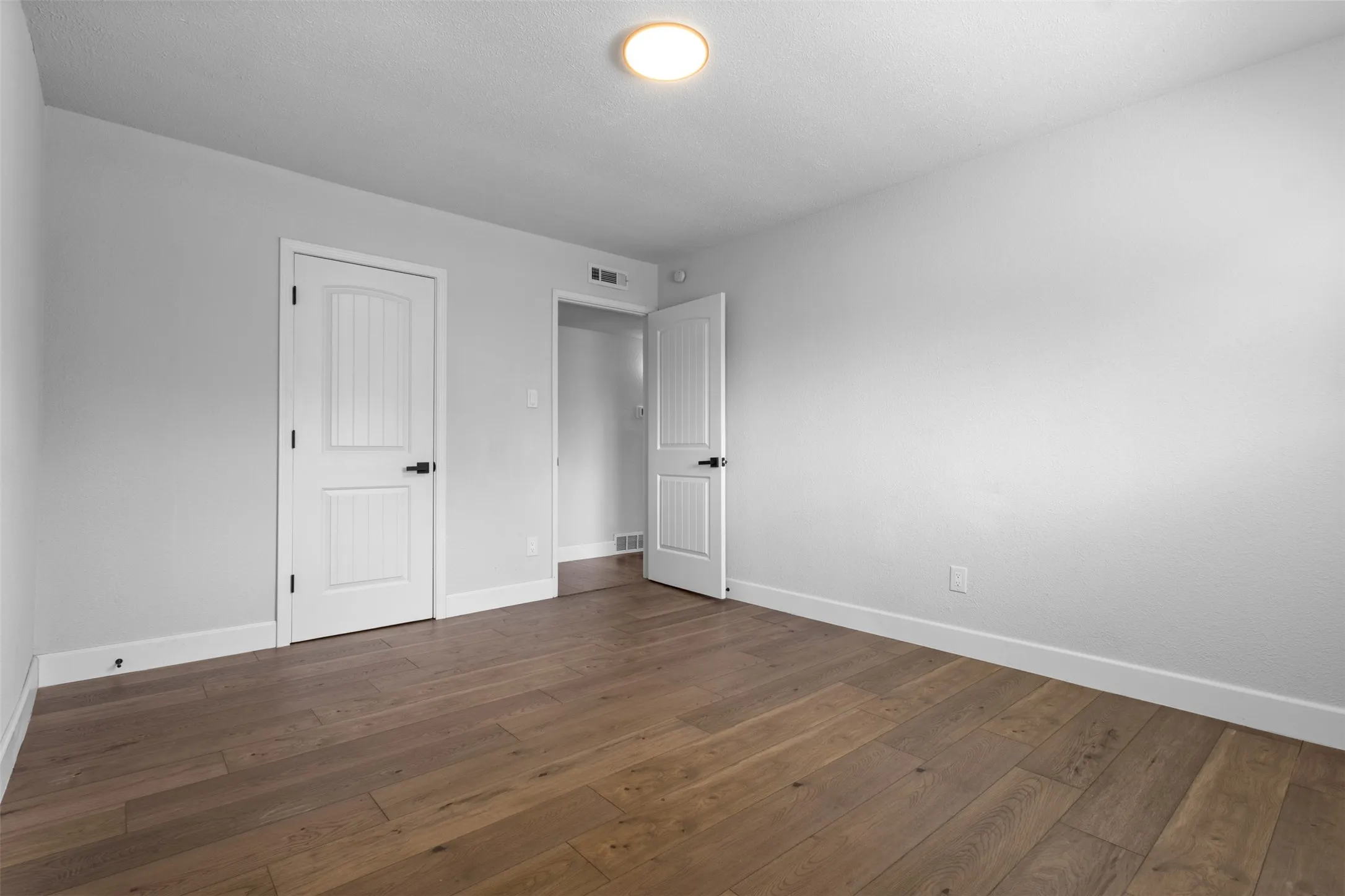 Wood-finish flooring, white walls, white trim, and a flush-mount ceiling light